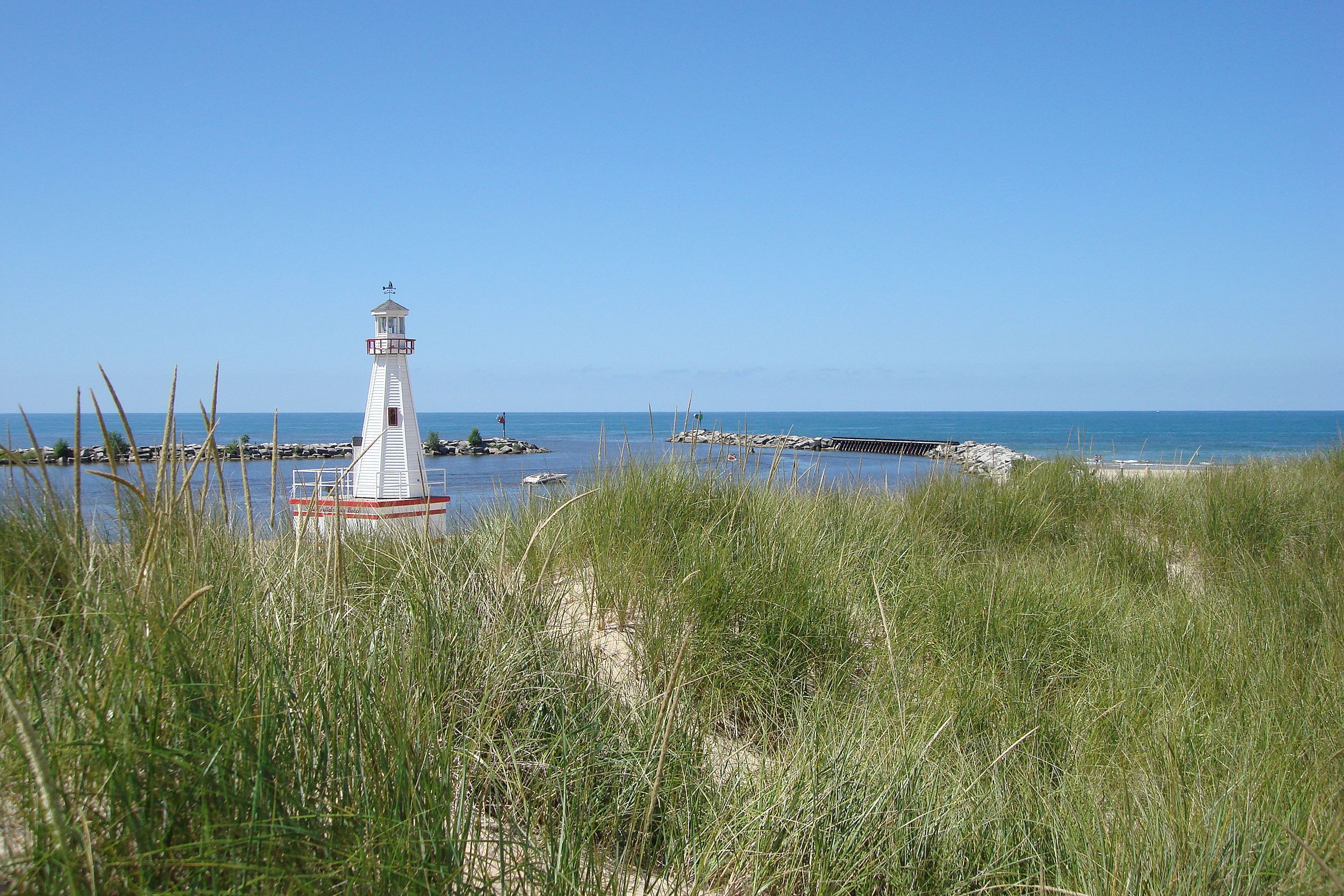 Lighthouse, New Buffalo, Michigan, beach grass among white sand in the foreground, Lake Michigan and a clear blue sky on a sunny day