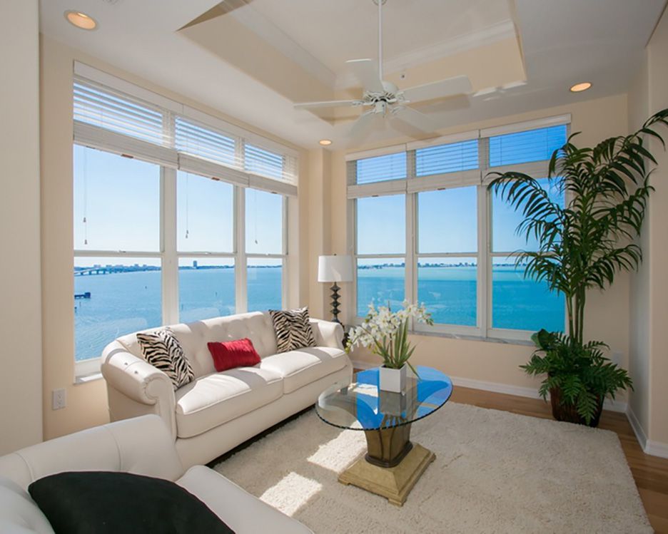 White sofa in front of corner windows with view of water in Sarasota Bay Club, Florida