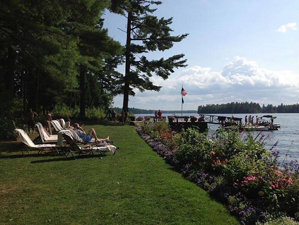 Man on lounge chair by lake at Migis Lodge Sebago Lake, Maine