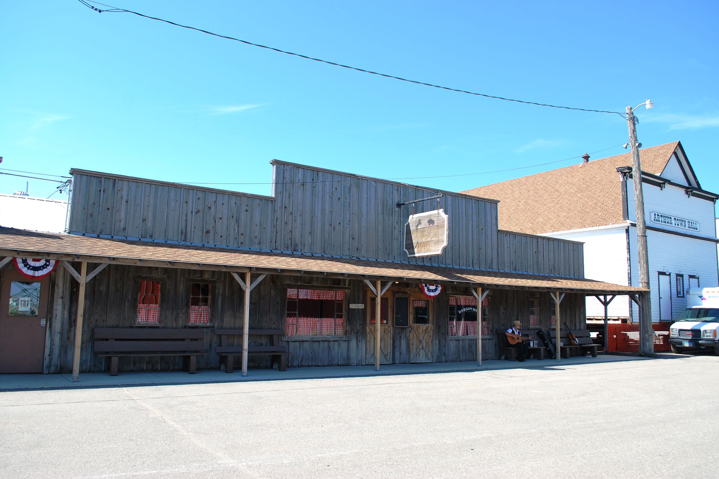 Old Wild West Historic Wooden Building, Bonanzaville, North Dakota, historic white building to the right, paved road in the foreground, on a sunny day