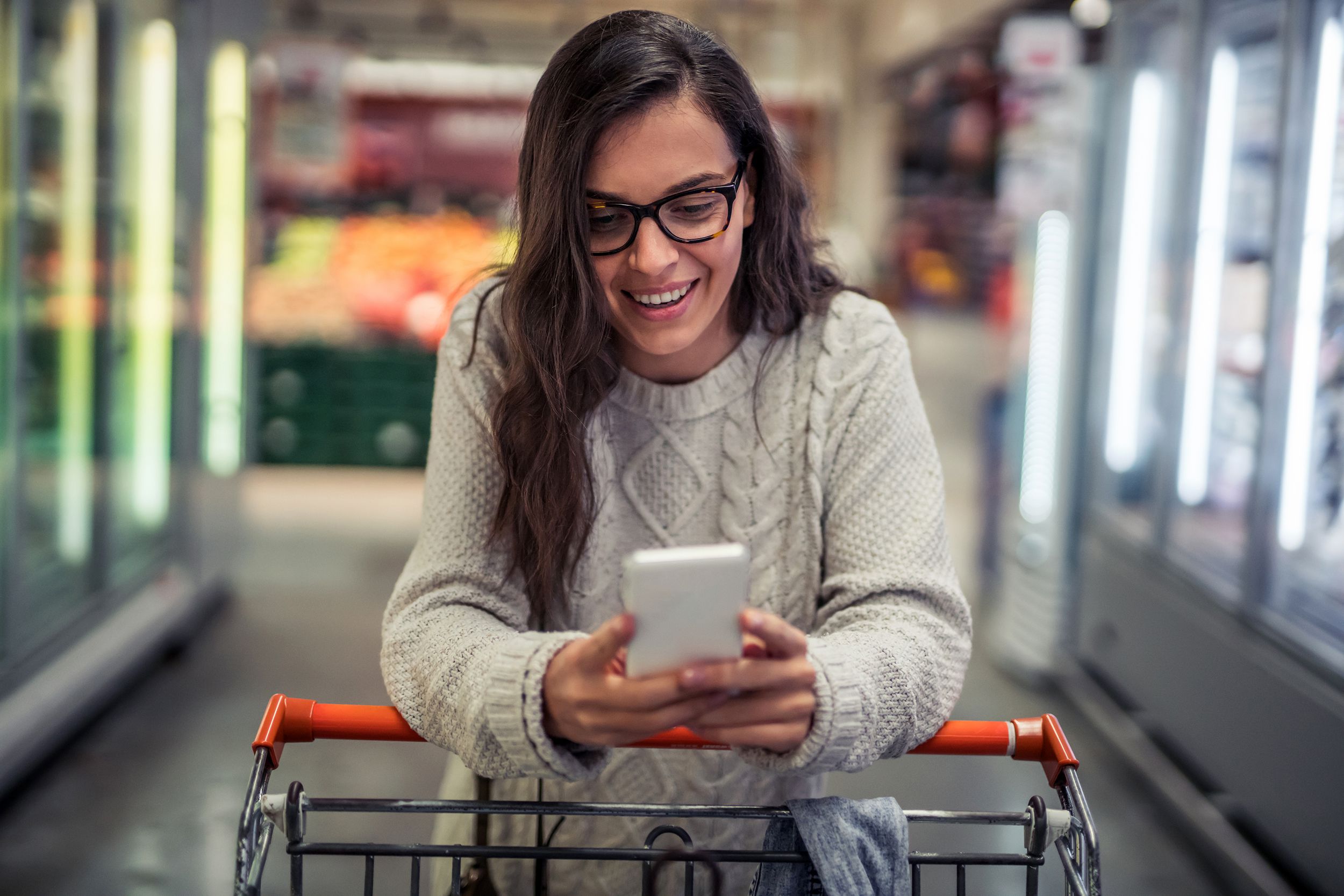 Woman looking at phone while in the grocery store