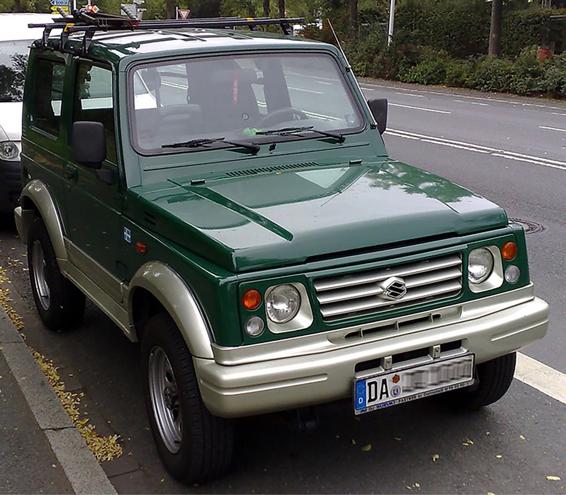 Dark green Suzuki Euro-spec Samurai parked on street in summer.