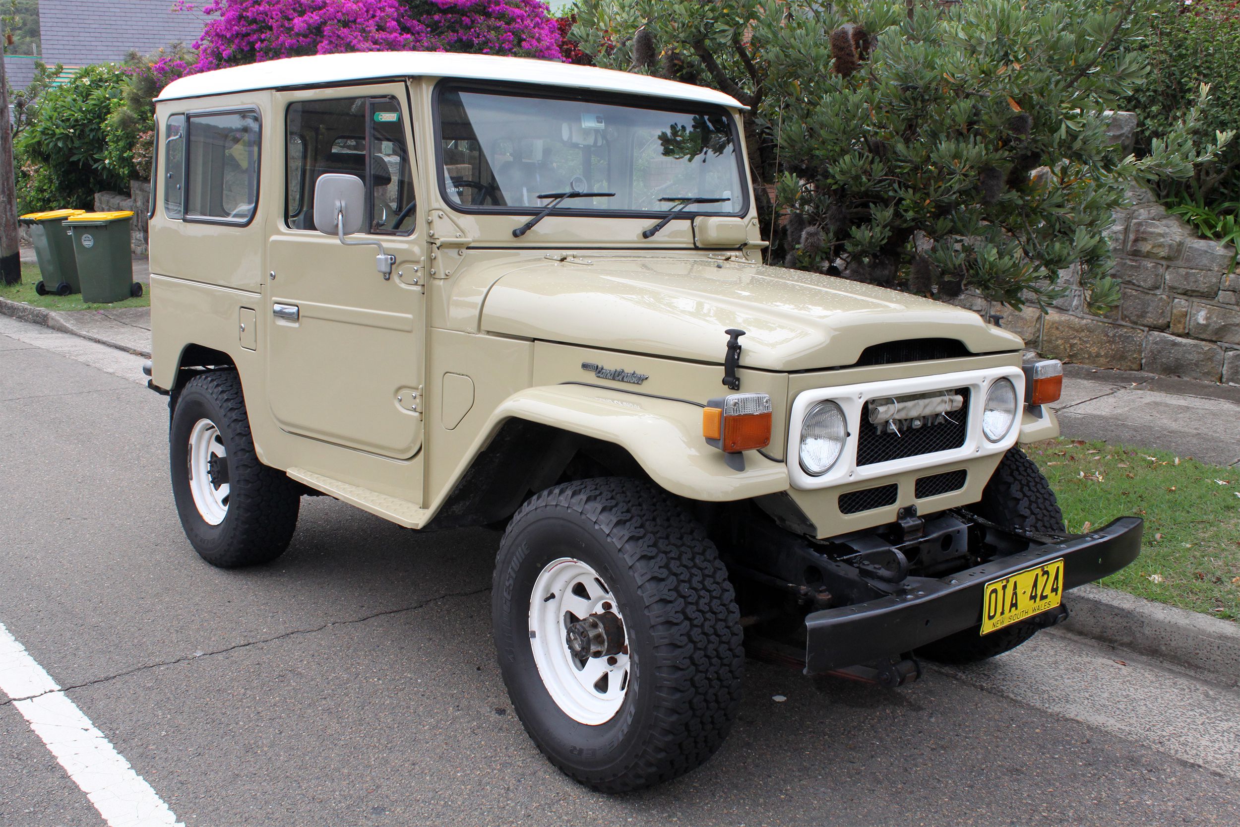 Beige Toyota Landcruiser FJ40 parked on a street in summer