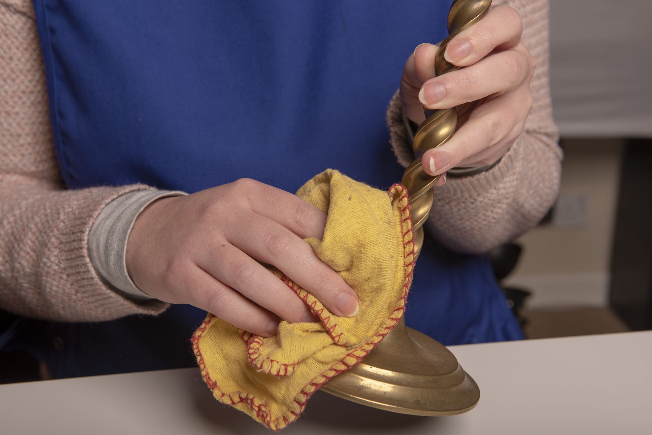 Unrecognisable woman cleaning brass candle sticks