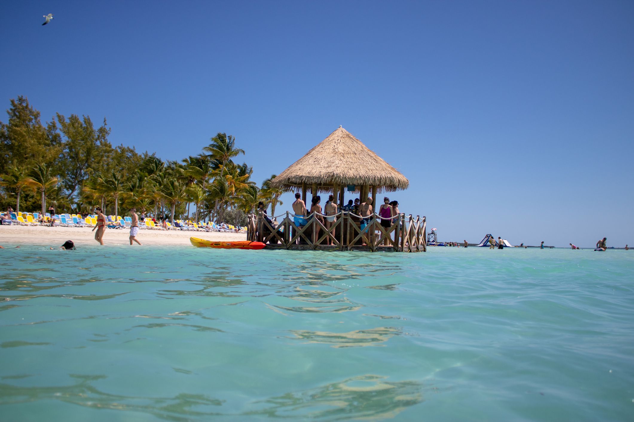 CocoCay, Bahamas 6th April 2019: Swim up ocean bar in the sea on a sandy beach with people enjoying sun and fun on a sunny day at this tropical island.