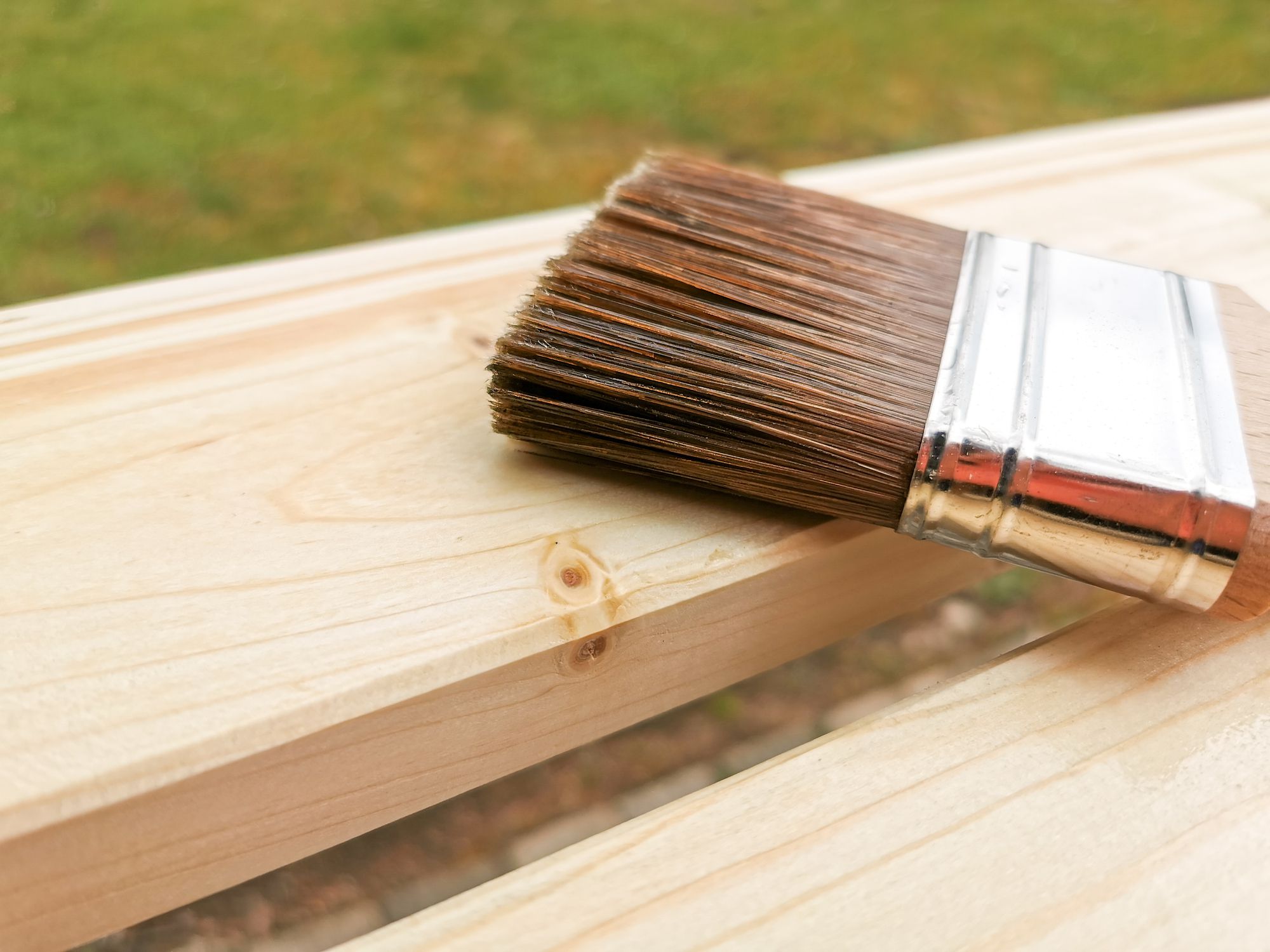 a paint brush lying on two pine wood boards