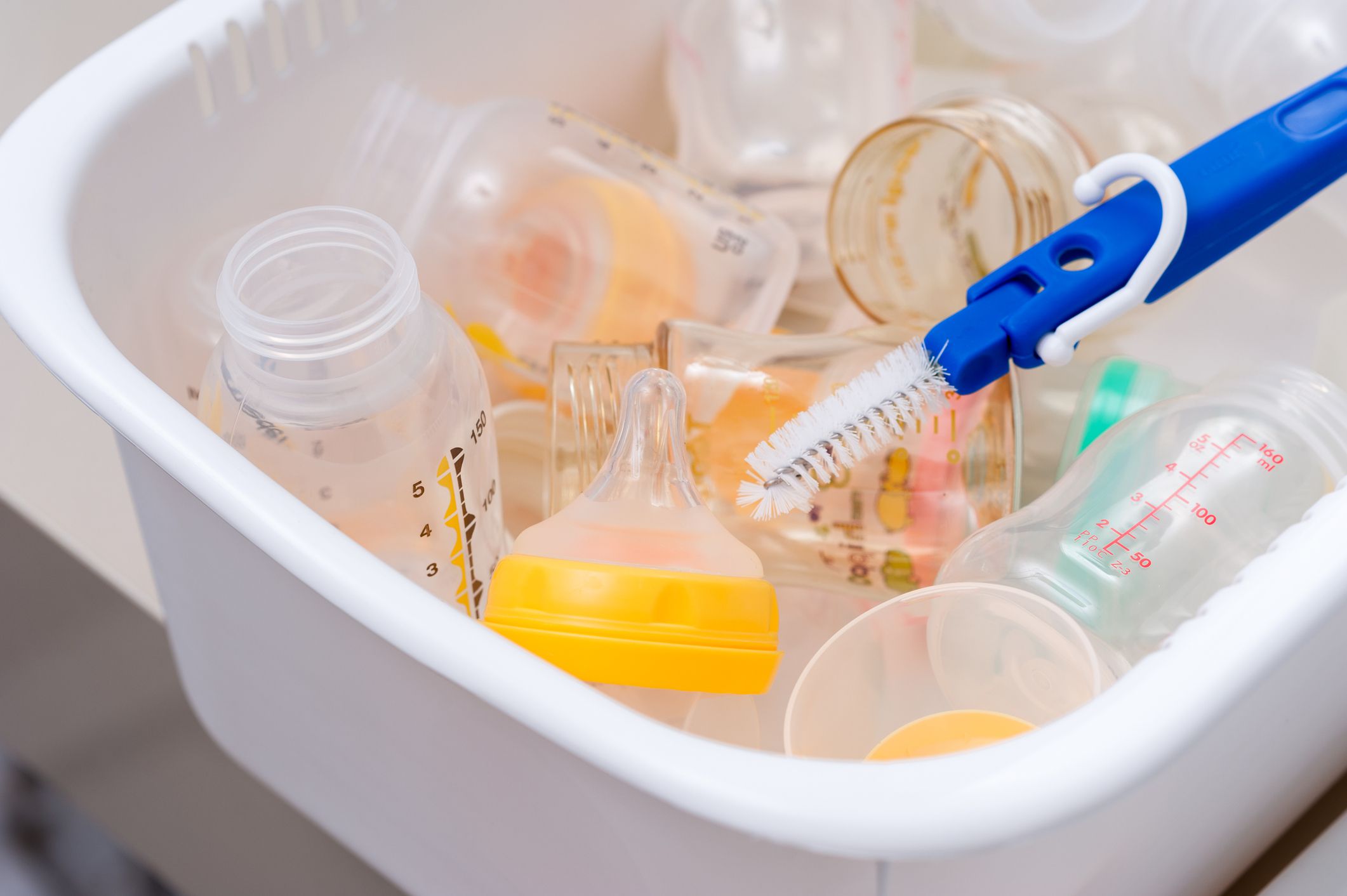 washing baby bottles and nipples with soft bottle brush and dishwashing liquid