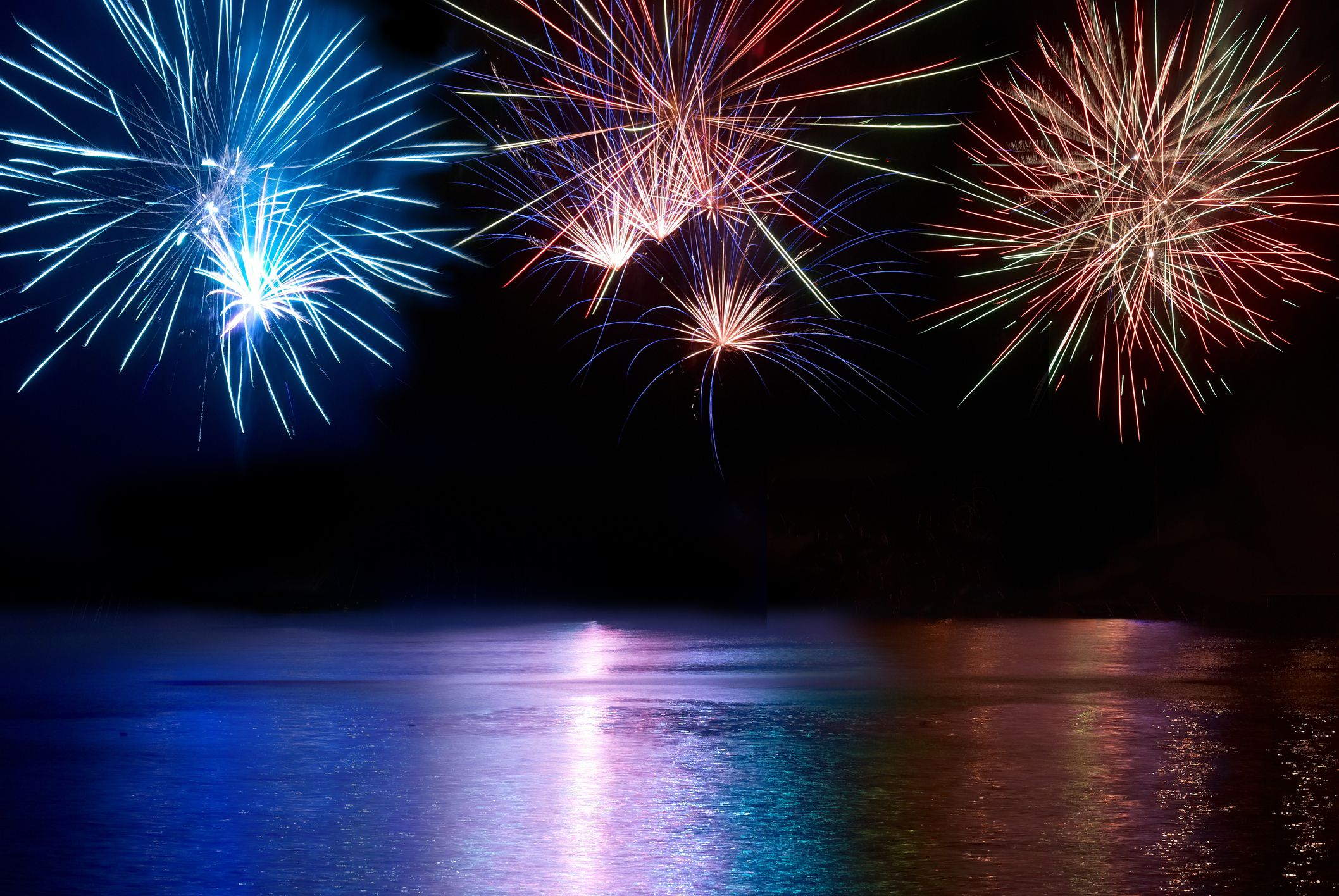 Blue, red and white colorful fireworks above the river. Holiday celebration.