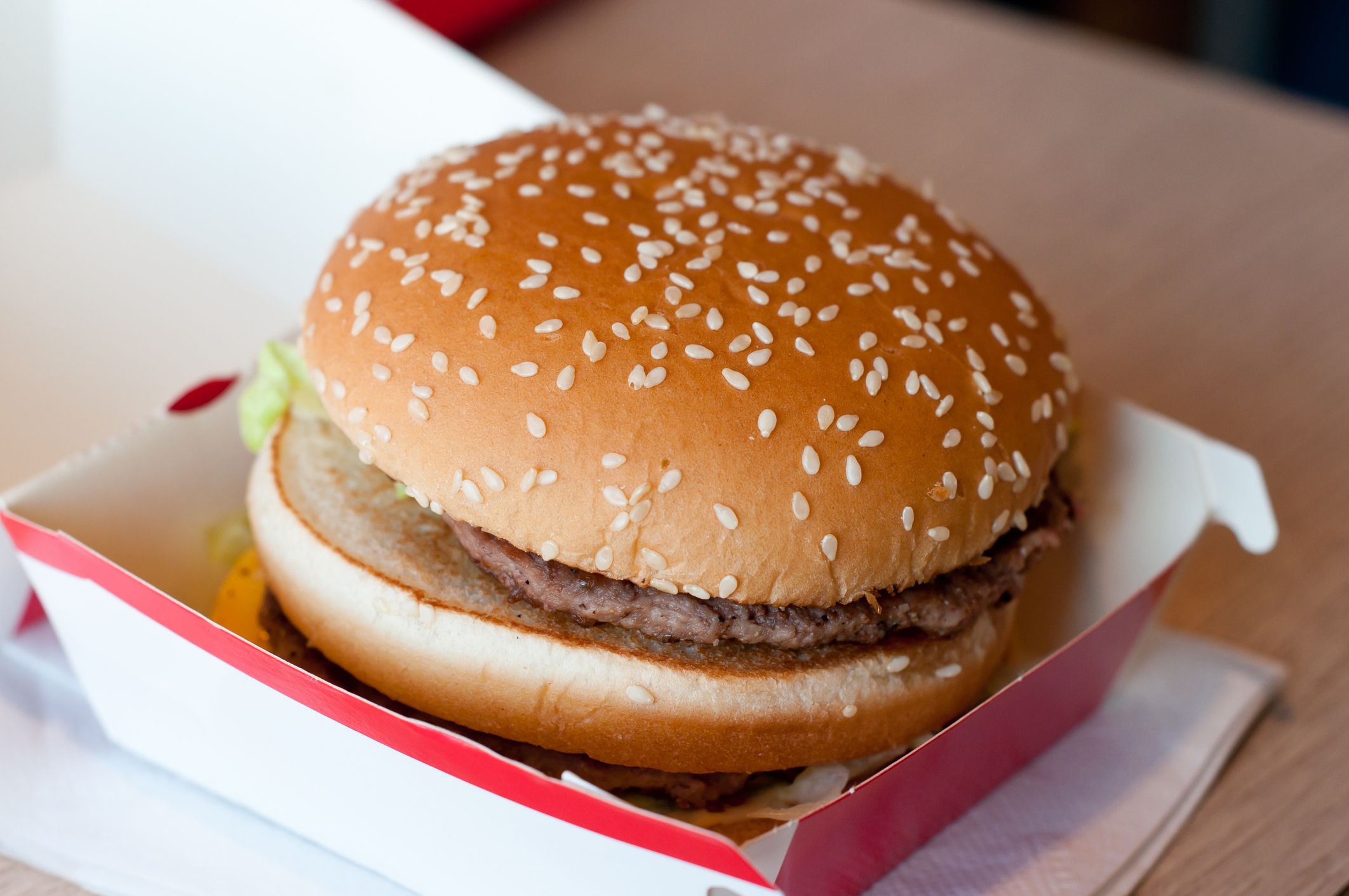 Unhealthy hamburger in the paper container in the natural light.