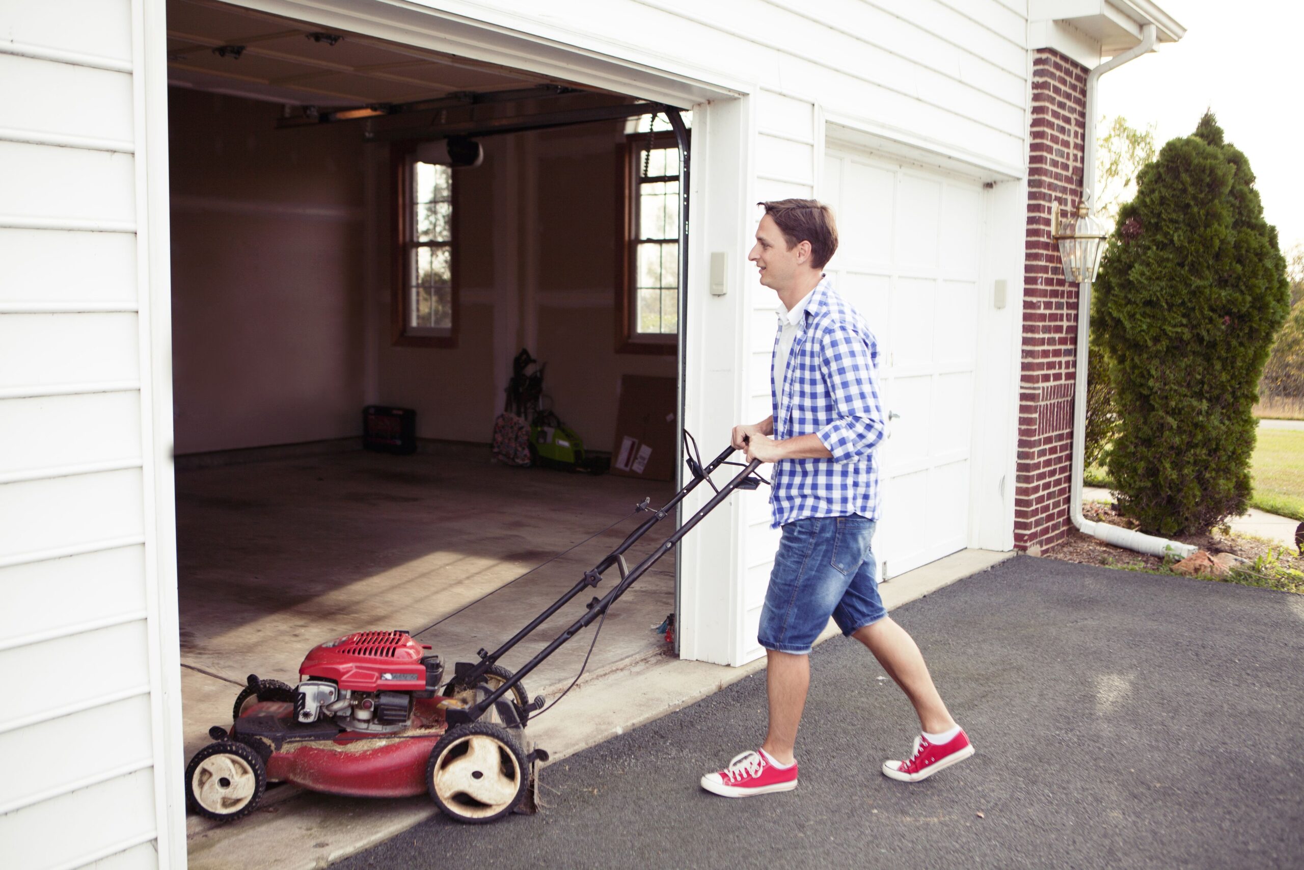 man putting lawn mower in the garage