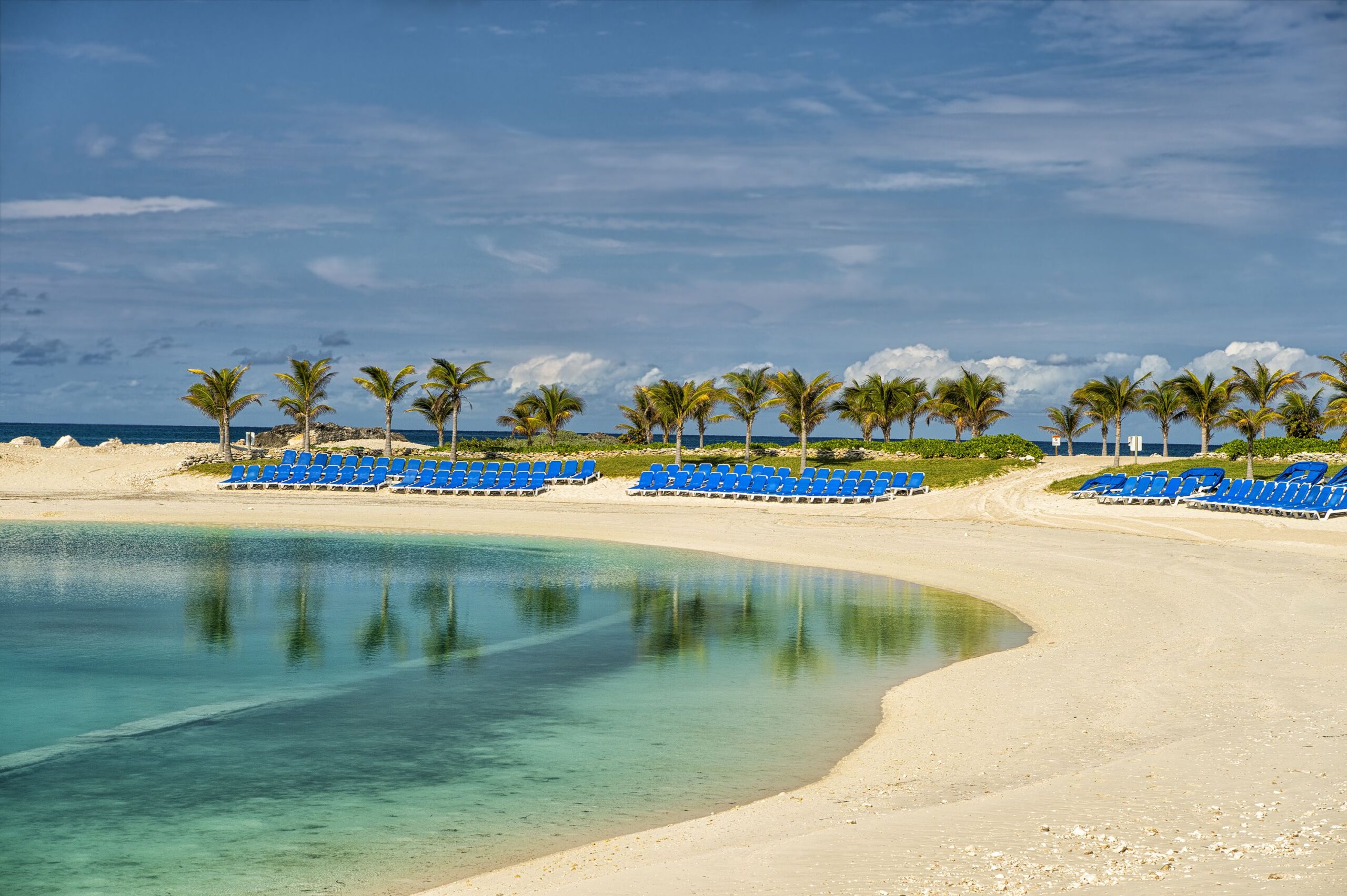 Beautiful bahamian beach with tropical plants of green palm trees blue clean atlantic ocean water and sandy coast in sunny summer weather in Great Stirrup Cay, Bahamas