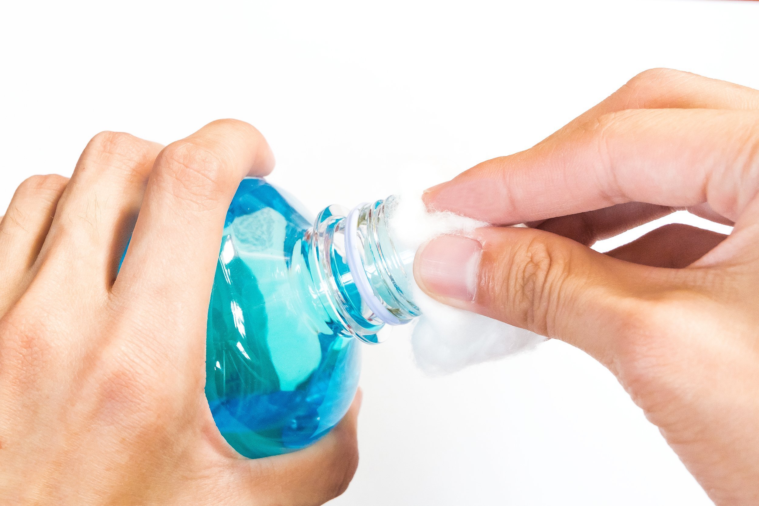 man holding ethyl alcohol bottle and cotton ball