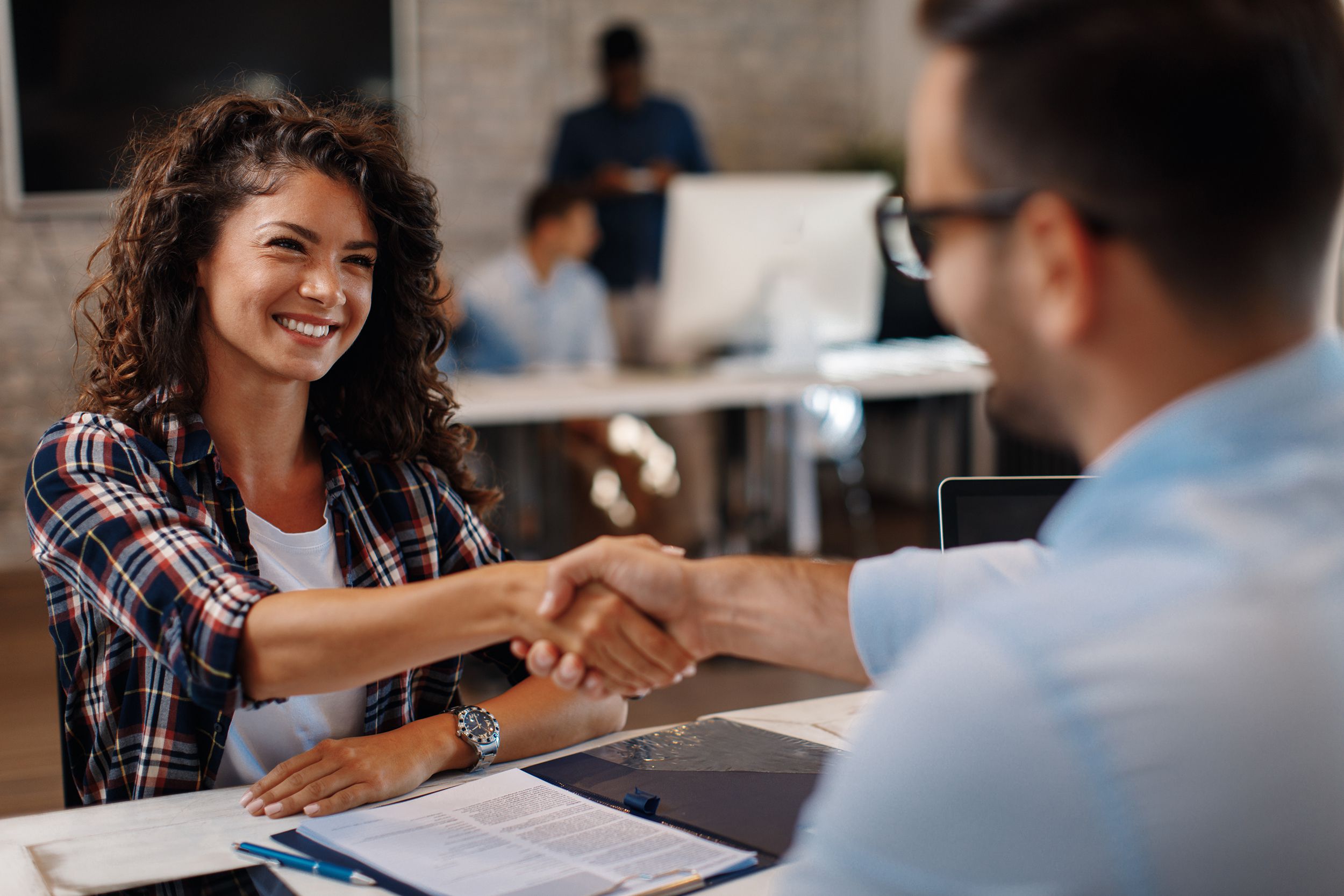 multi-ethnic woman shaking hands with man at a recruiter session