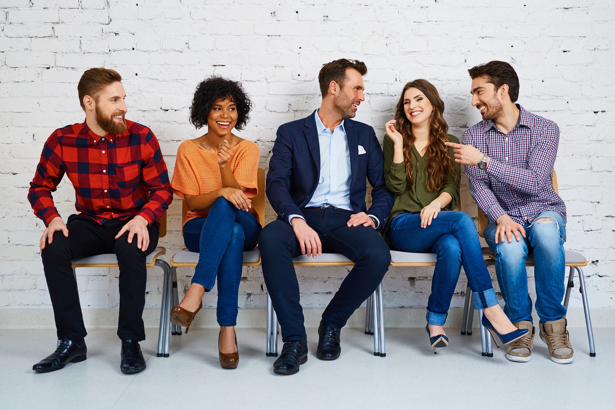 group of happy young people waiting in chairs at job interview