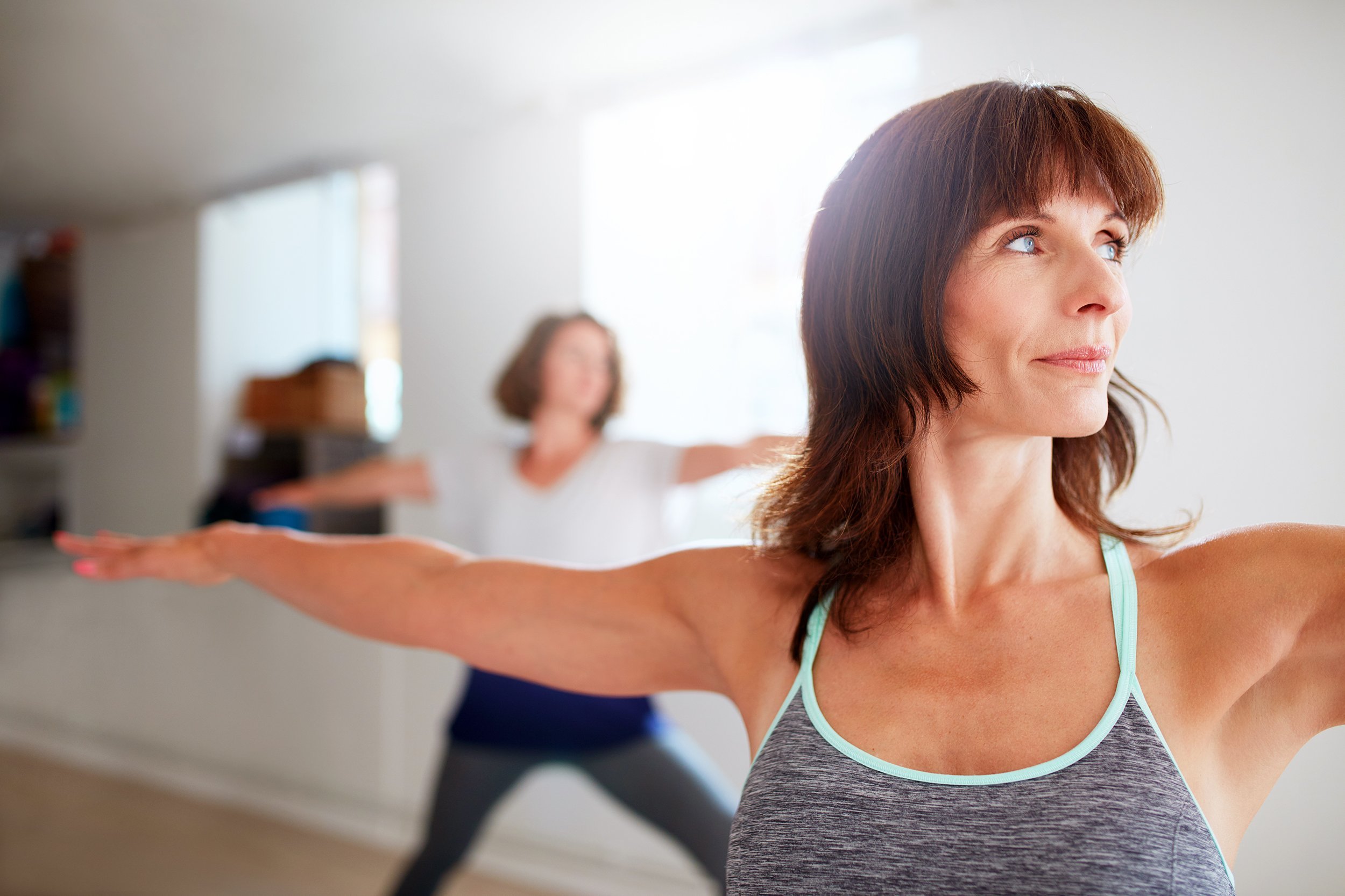 Portrait of beautiful young woman doing the warrior pose during yoga class