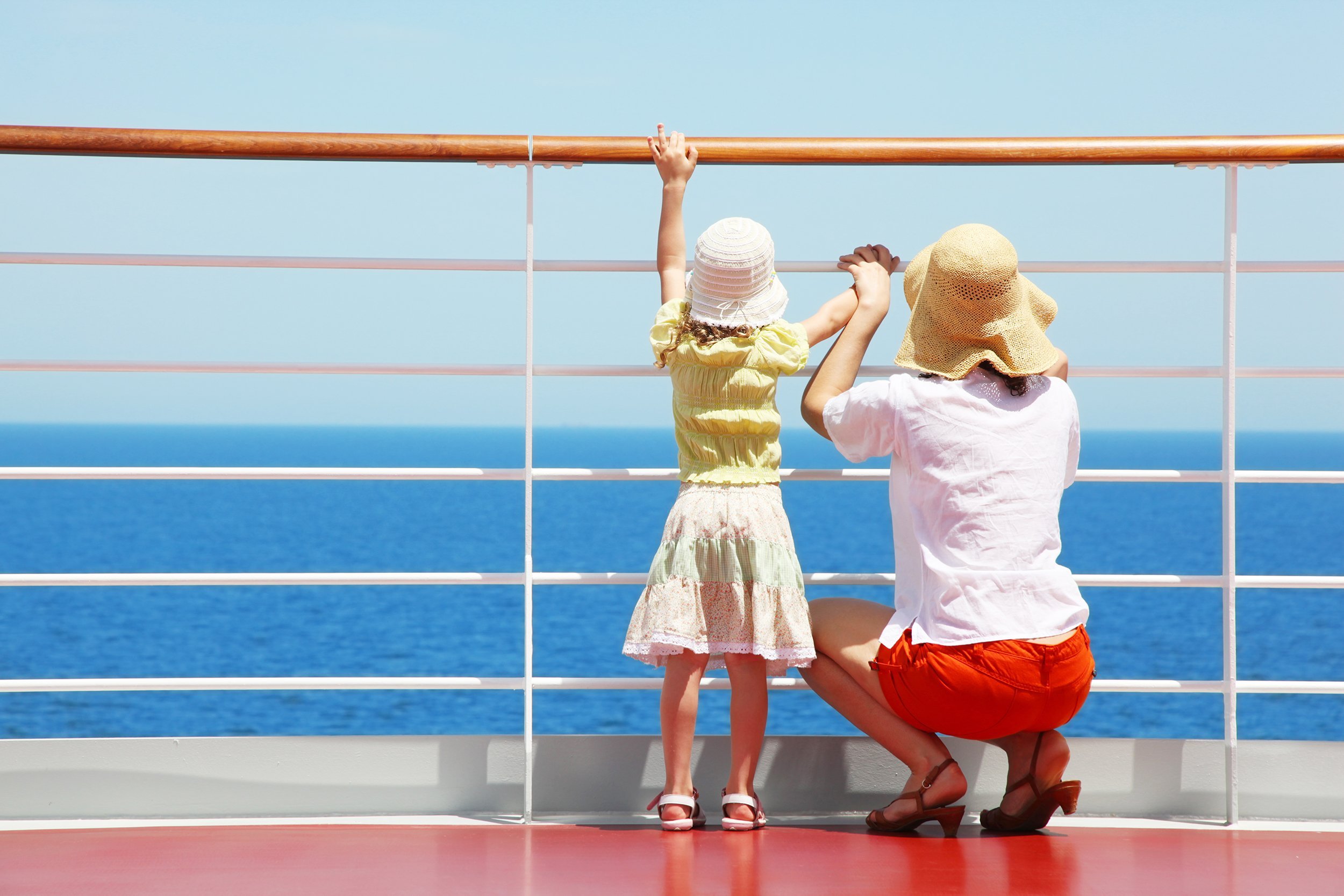 mother and her daughter standing on deck of cruise and they look far aboard