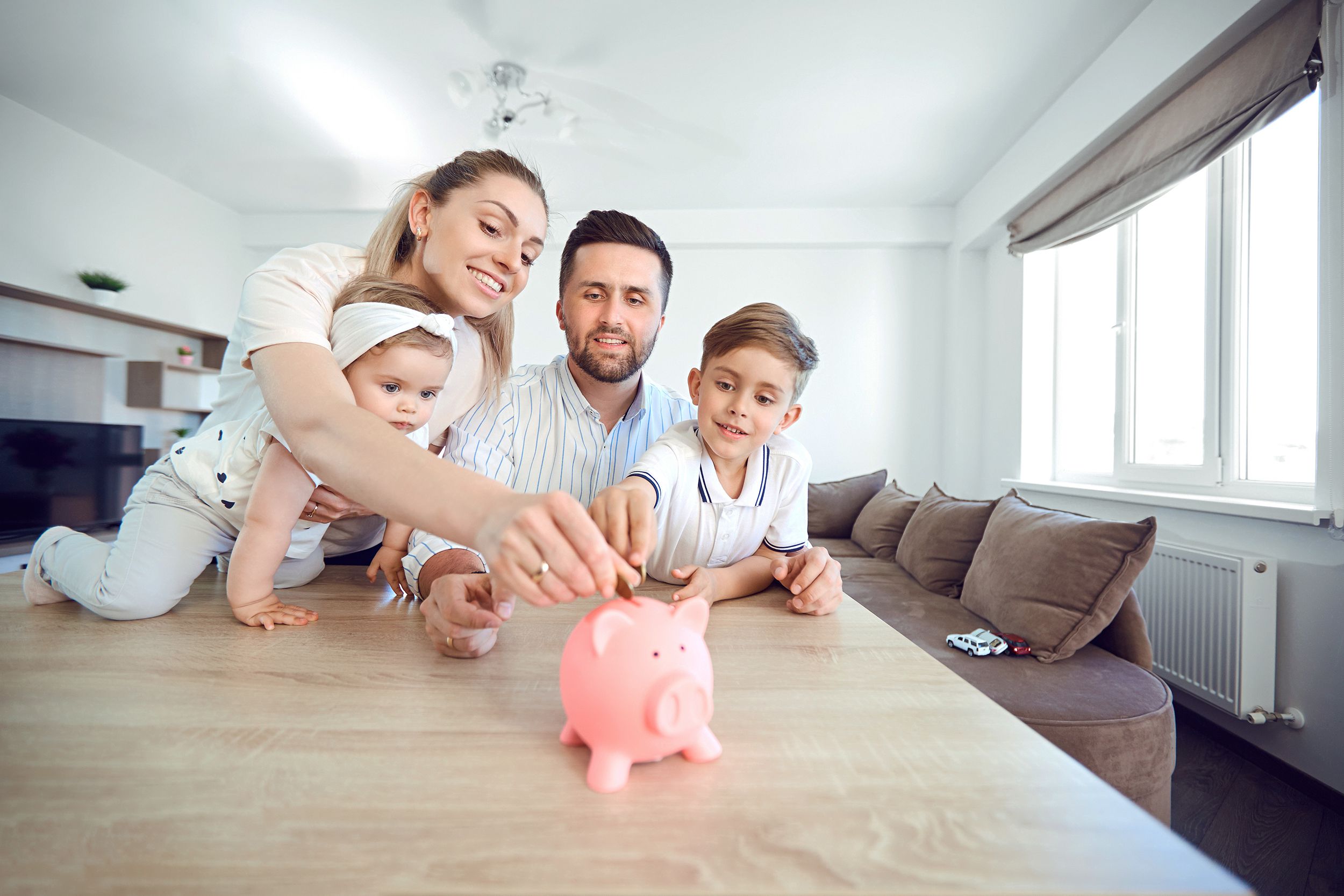 smiling family saves money with a piggy bank. Happy family at the table in the room