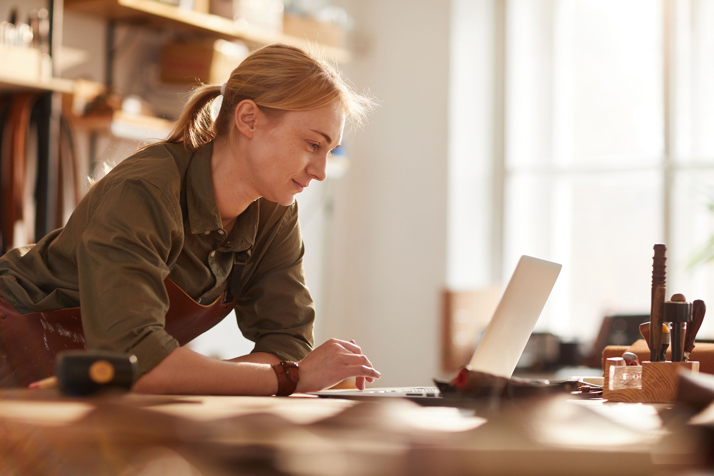 female artisan using laptop in crafting workshop