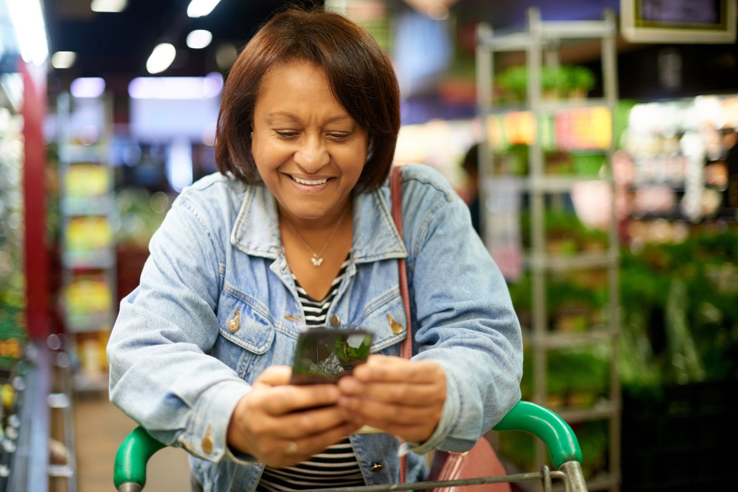 mature woman using her cellphone while out shopping in a grocery store