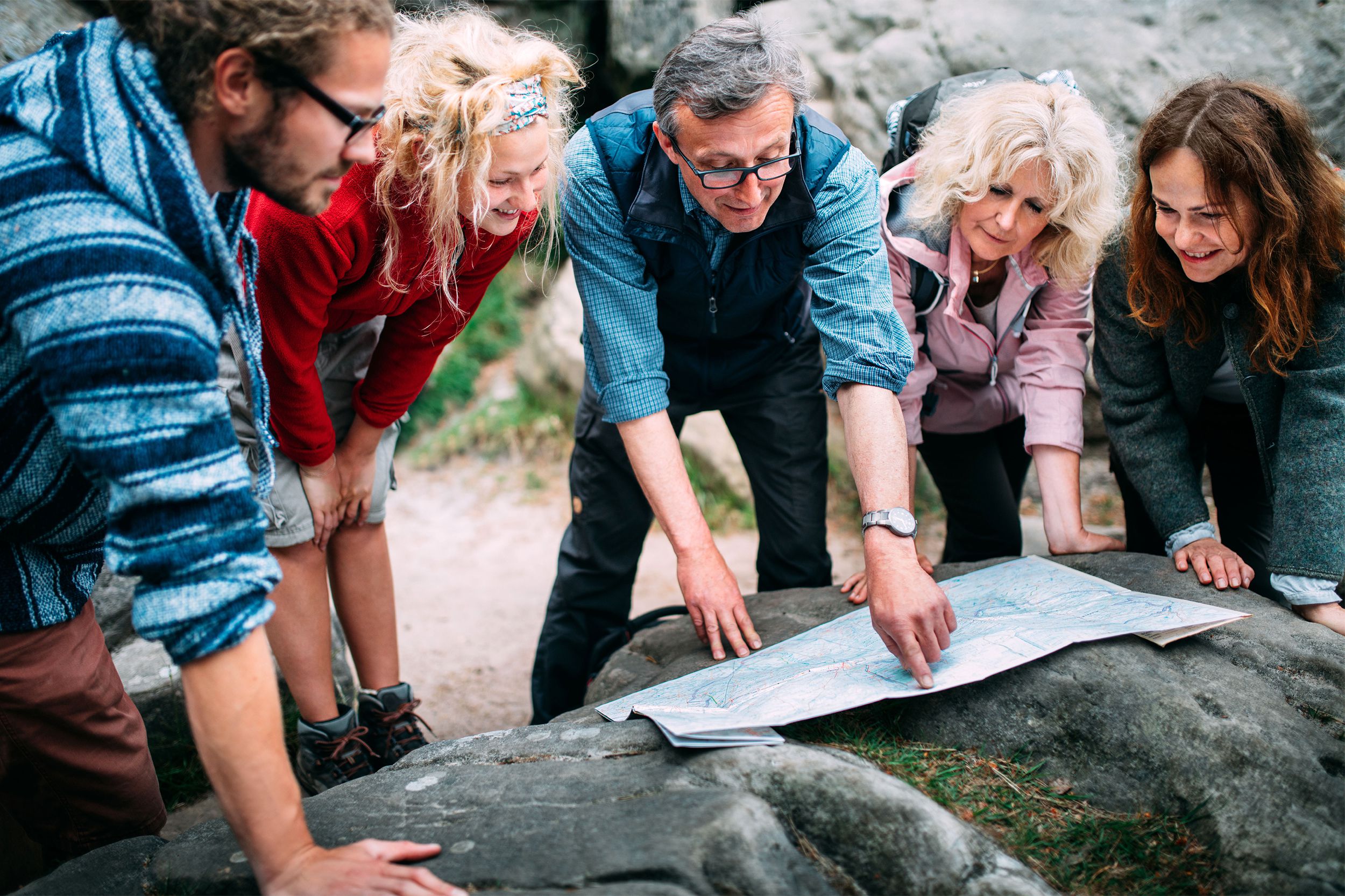 Senior man pointing to a map with a group of tourists