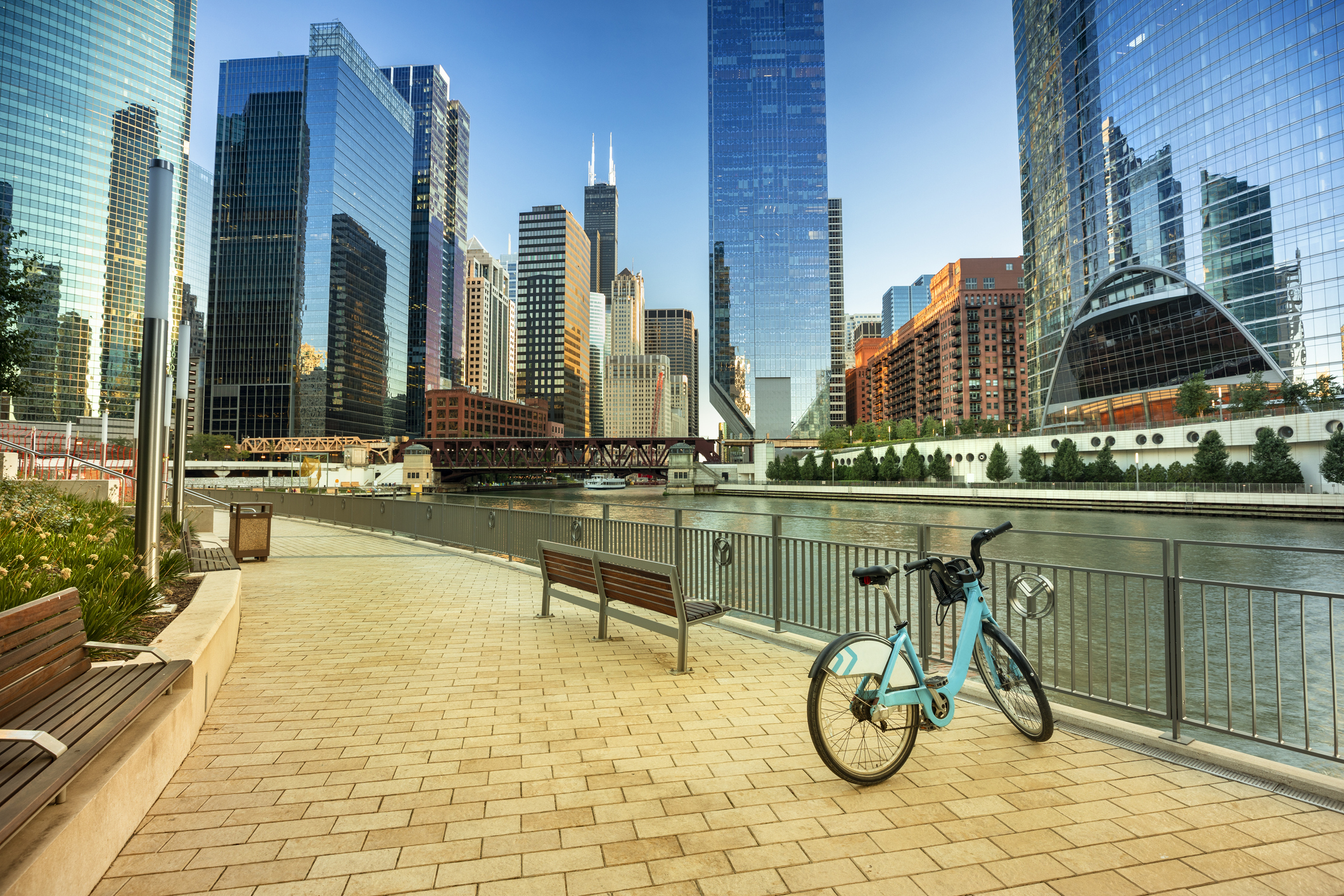 Bike parked along the Riverwalk in downtown Chicago, river and downtown skyscrapers, during a summer day