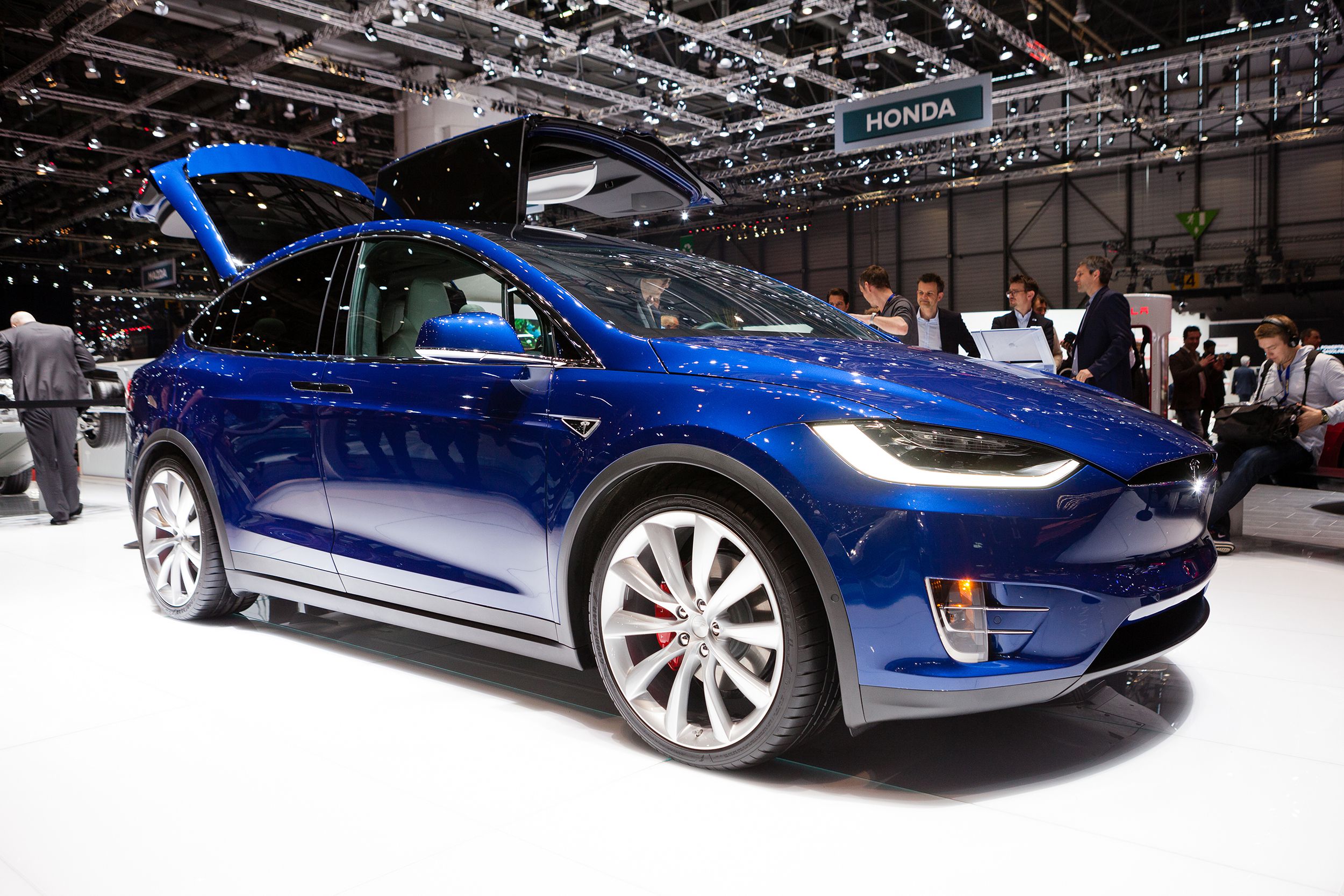Side-view of blue Tesla Model X, facing the right, at the Geneva Motor Show on March 1, 2016 in Geneva, Switzerland, white floor and bright lights above