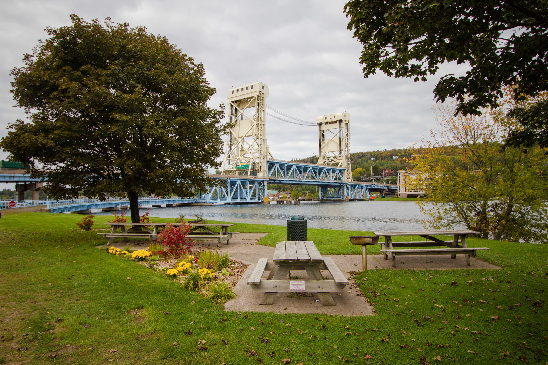 Bridgeview Park in Waterfront District of Downtown Houghton, Michigan, park in the foreground with Portage Canal Lift Bridge in the background, during summer, grey clouds cover the sky