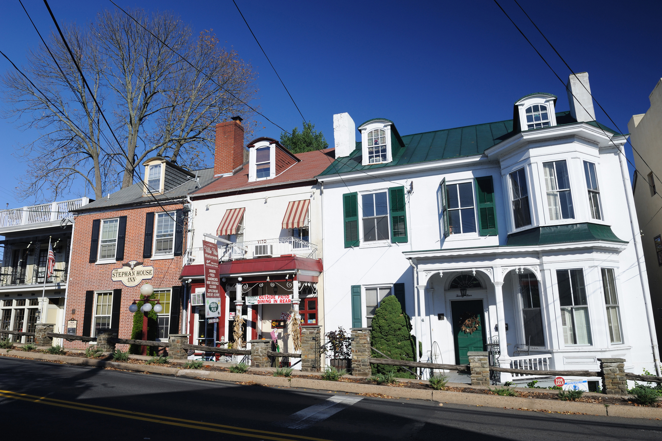 Colonial storefronts along road of New Hope, Pennsylvania, sidewalk with historic feel, a blue sky in the background and bare trees during winter