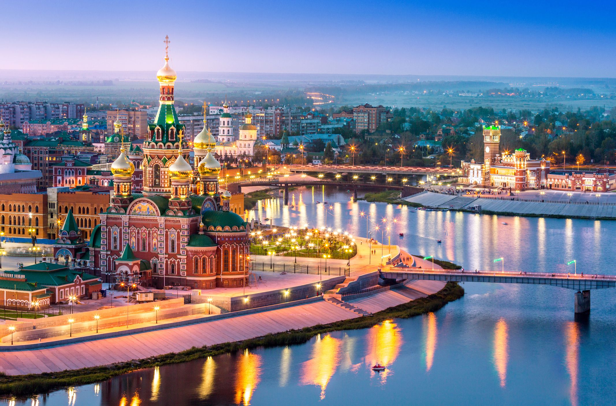 Downtown Yoshkar-Ola in Volga region of Russia during late sunset with Kokshaga River snaking from the foreground and going into the background, city lights
