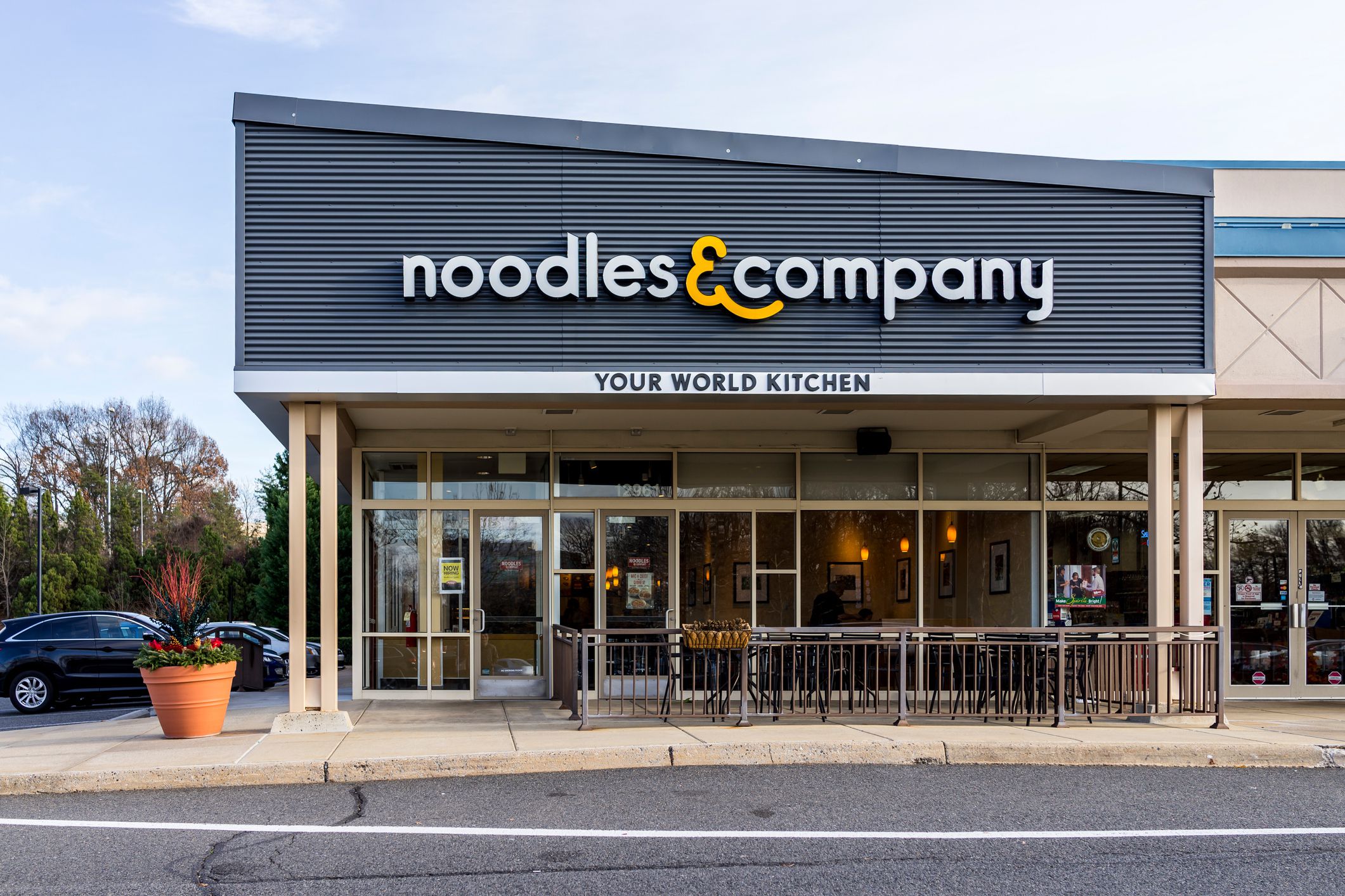 Exterior of Noodles & Company restaurant in Fairfax, Virginia with parking lot on the side