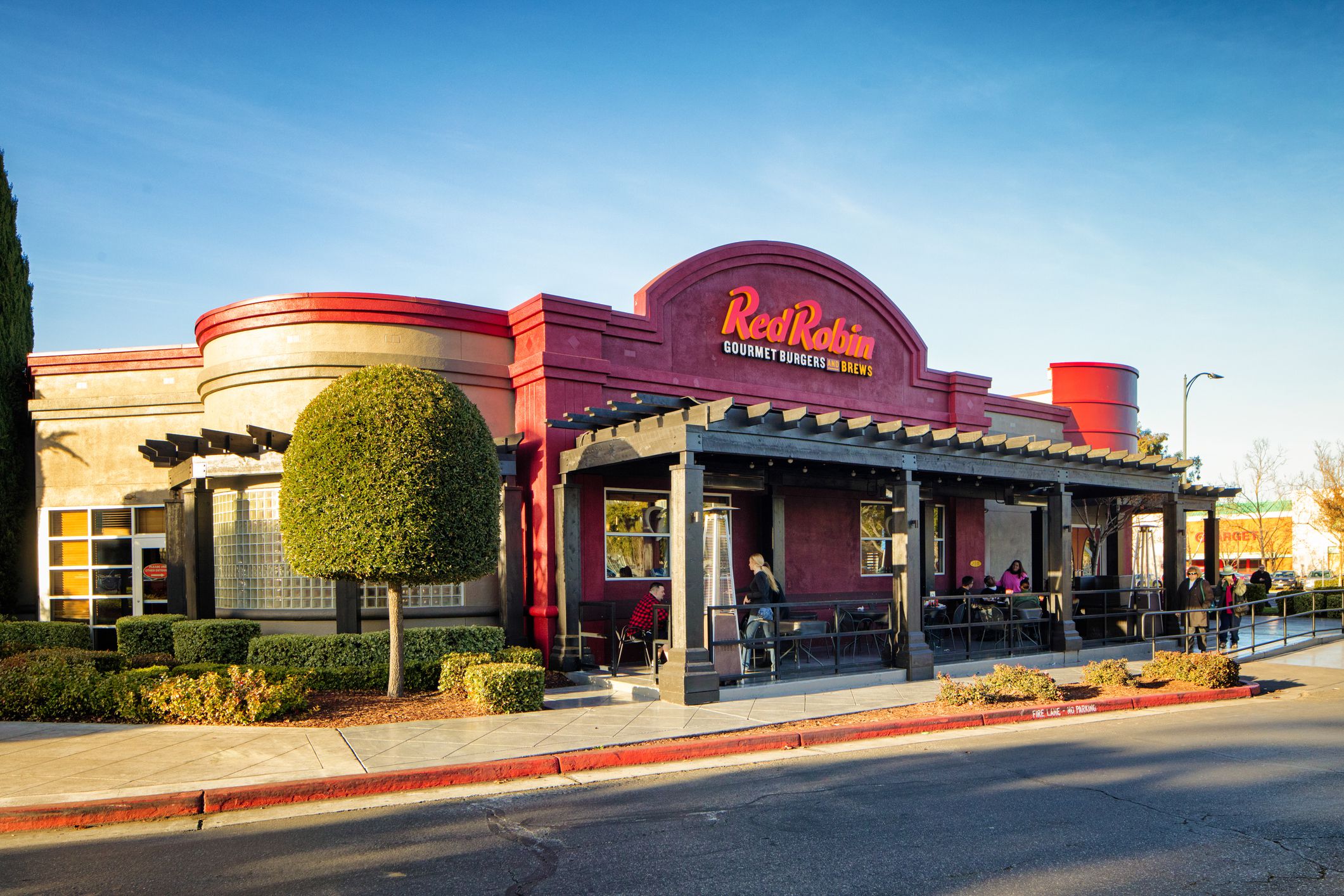 Exterior of a Red Robin restaurant in San Jose, California with people eating outside in a seating area
