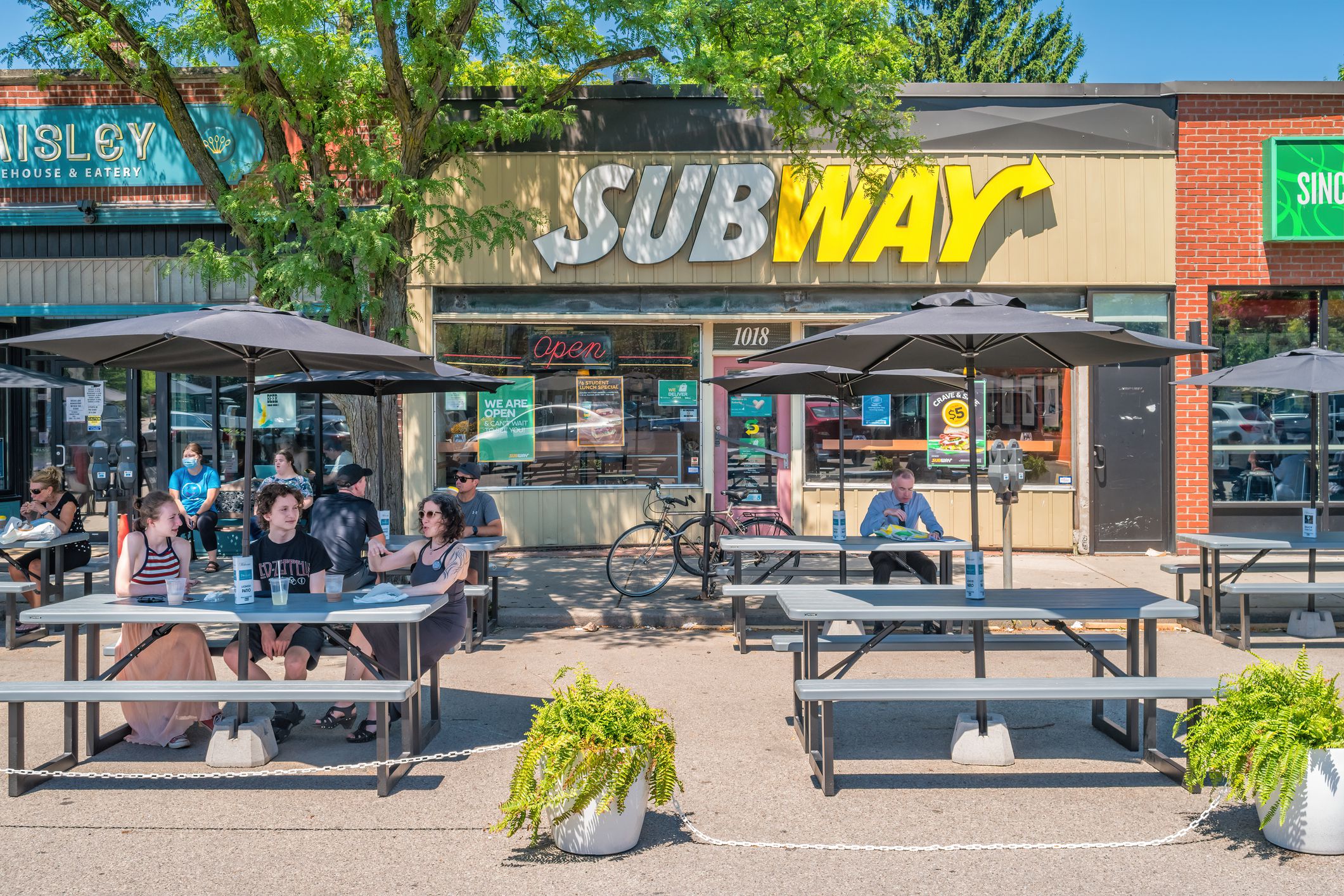 Exterior and outdoor eating area of a Subway restaurant in Hamilton, Ontario, Canada with people eating outside on a sunny, summer day