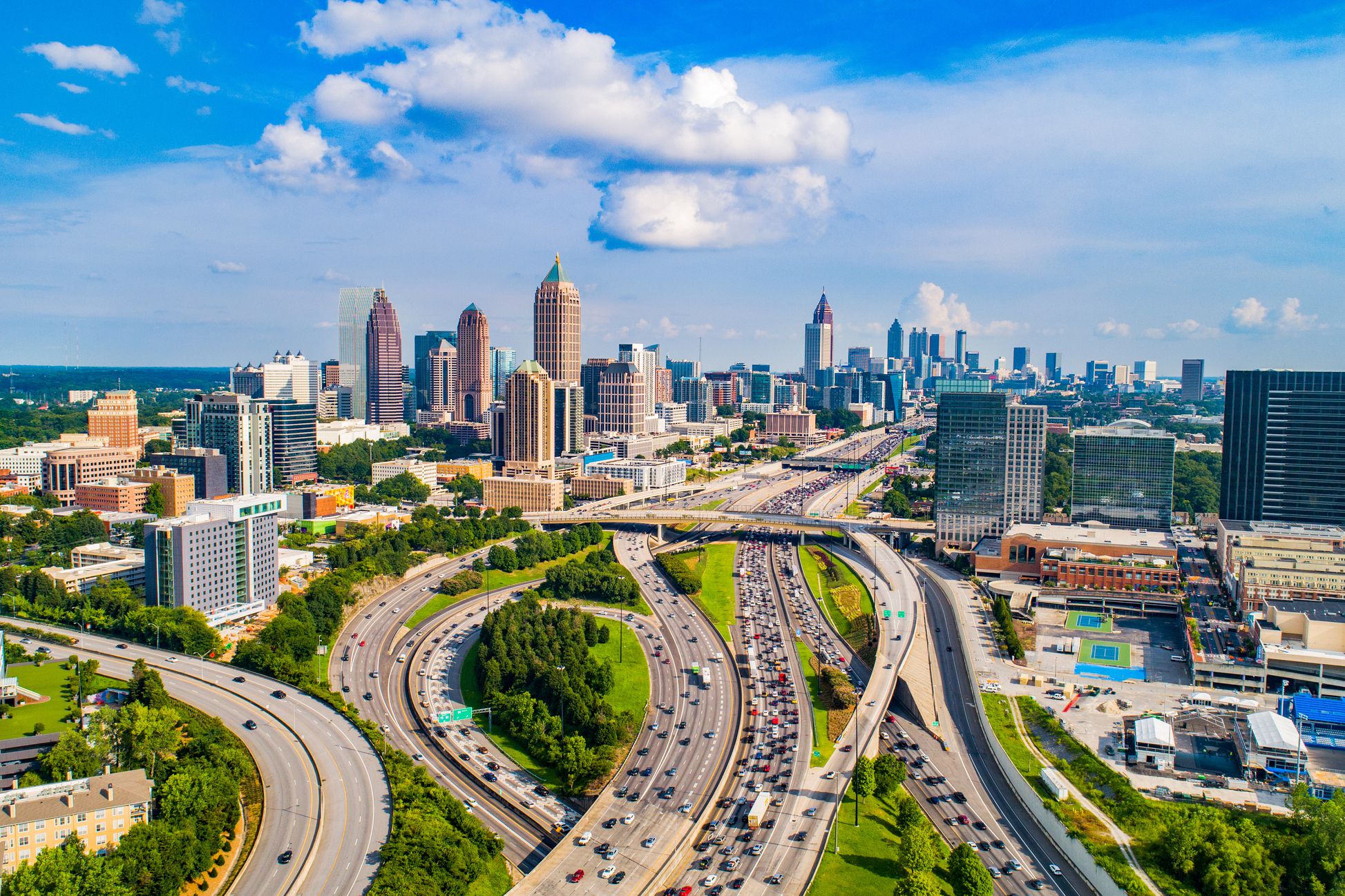 I-75 and I-85 junction in north downtown Atlanta, highway in the foreground, with buildings in the background outlined by a blue sky, during a sunny day in late spring