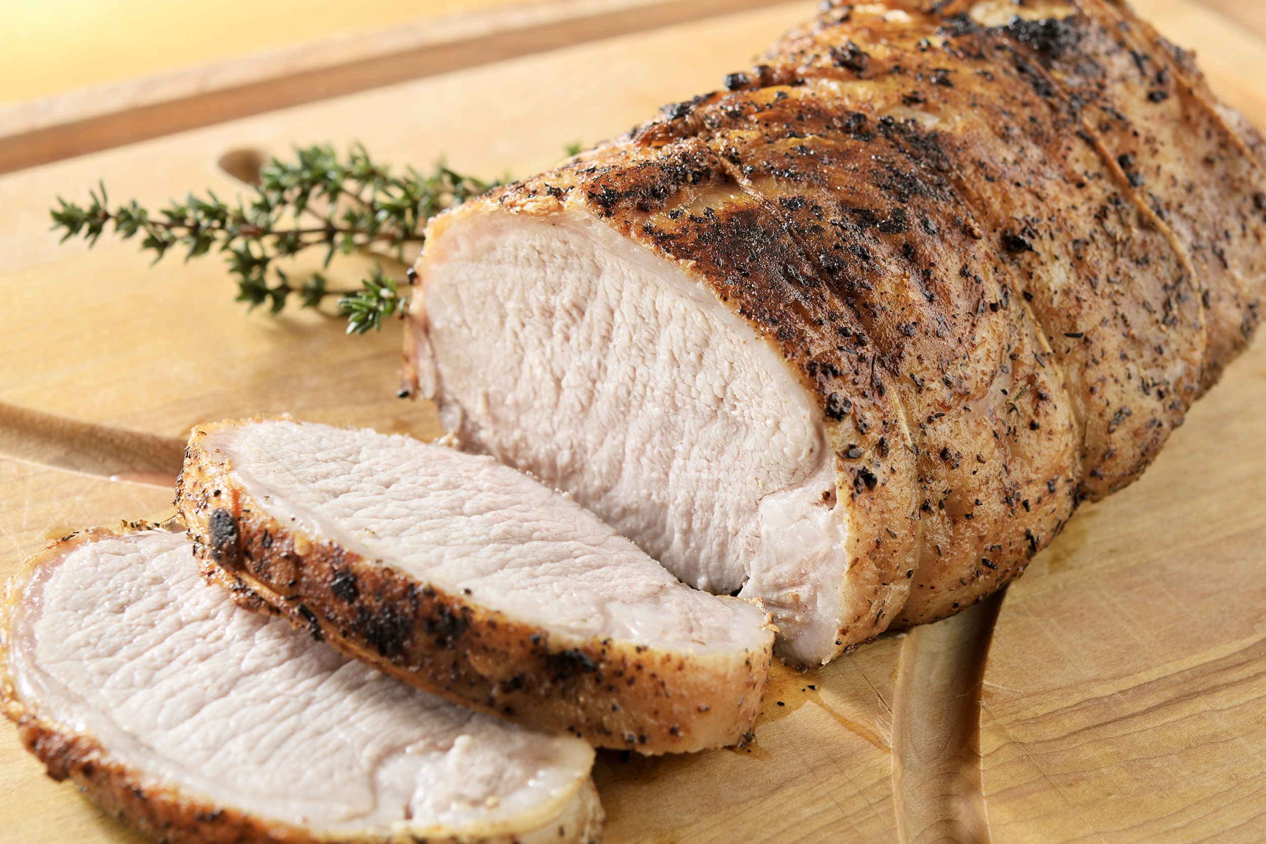Instant pot pork tenderloin on a decorative wooden cutting board with a blurred background