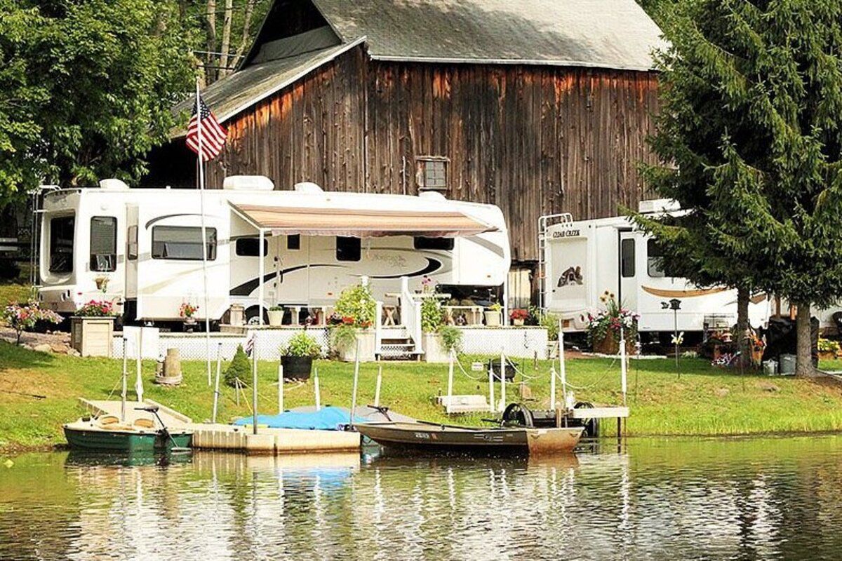 Keen Lake Camping & Cottage Resort, Waymart, Pennsylvania, an RV lot with lake and dock in the foreground and a barn and forest in the background
