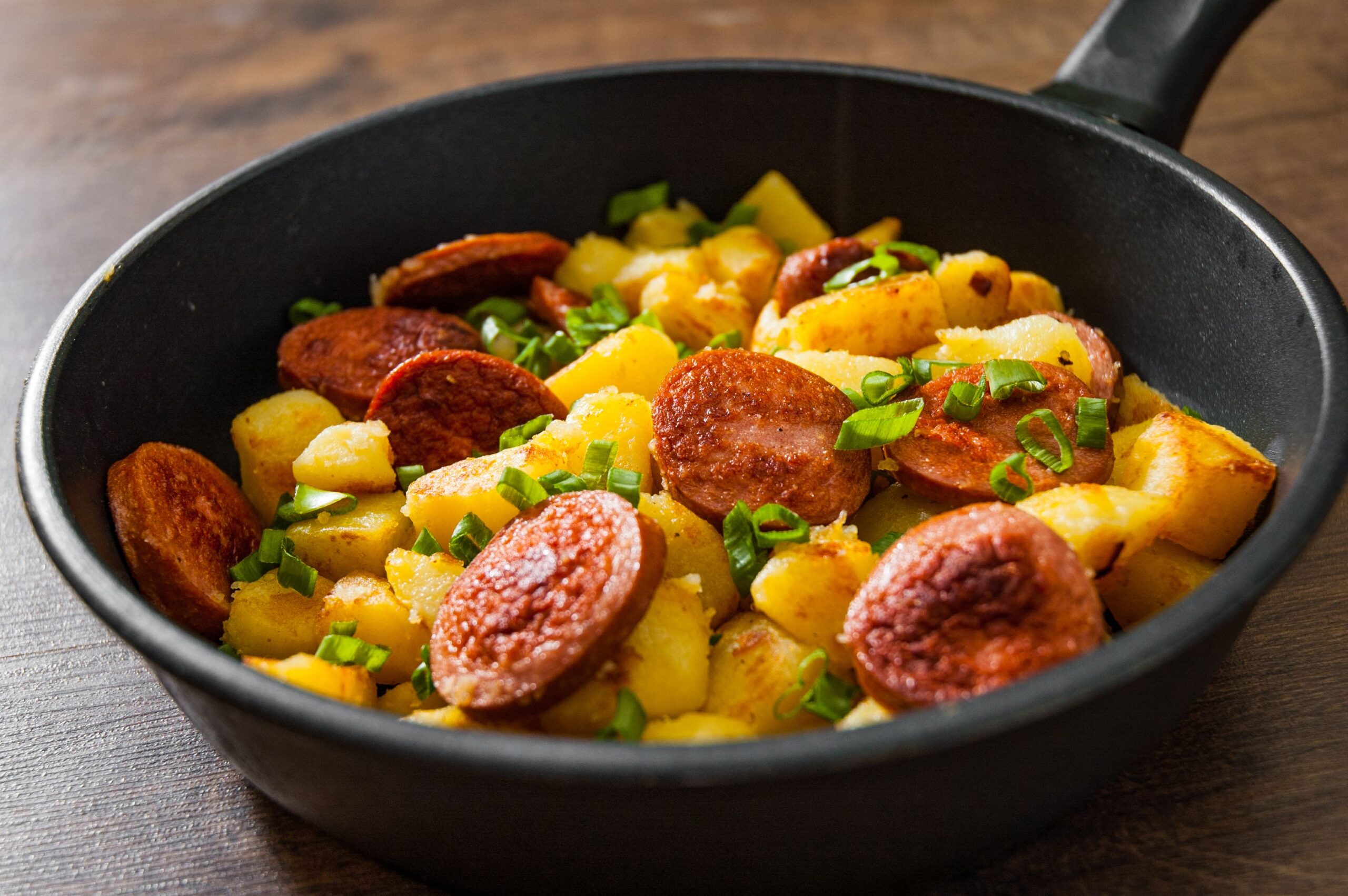 Kielbasa and potatoes skillet dinner in a skillet on a wooden table