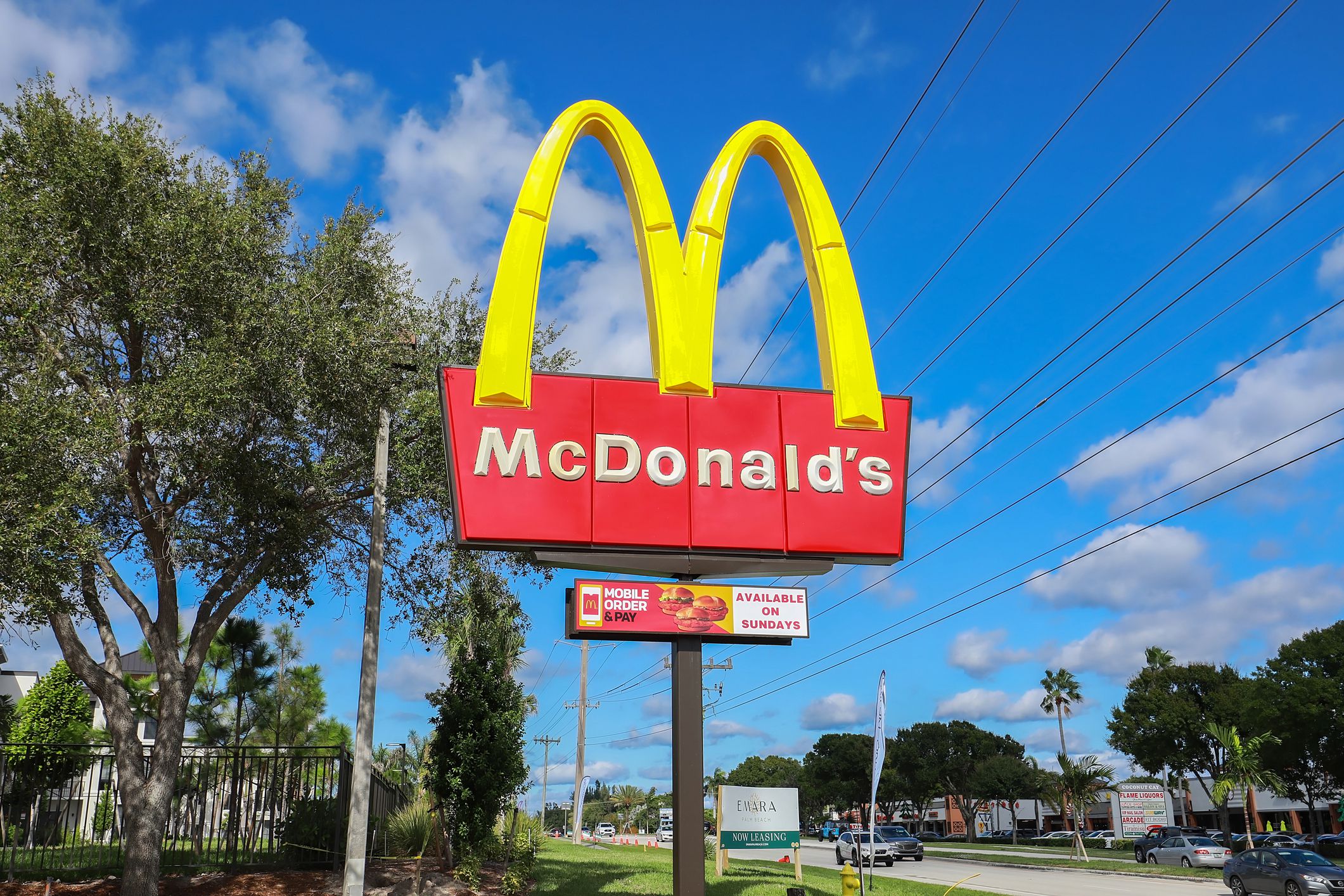 McDonald's restaurant sign in Juno Beach, Florida against a blue and white cloud sky with other establishments in the background