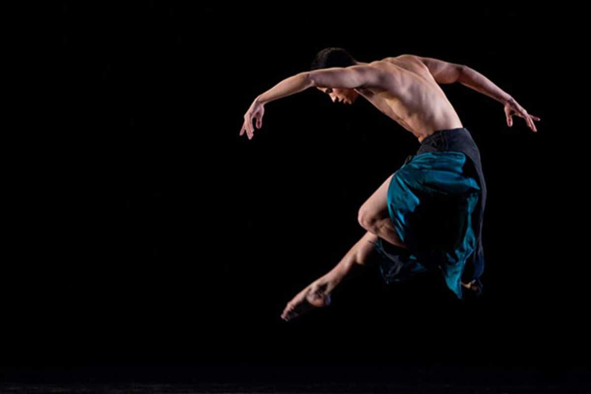 Man doing ballet during a performance at the Juilliard School, Manhattan, on the right, against a black background