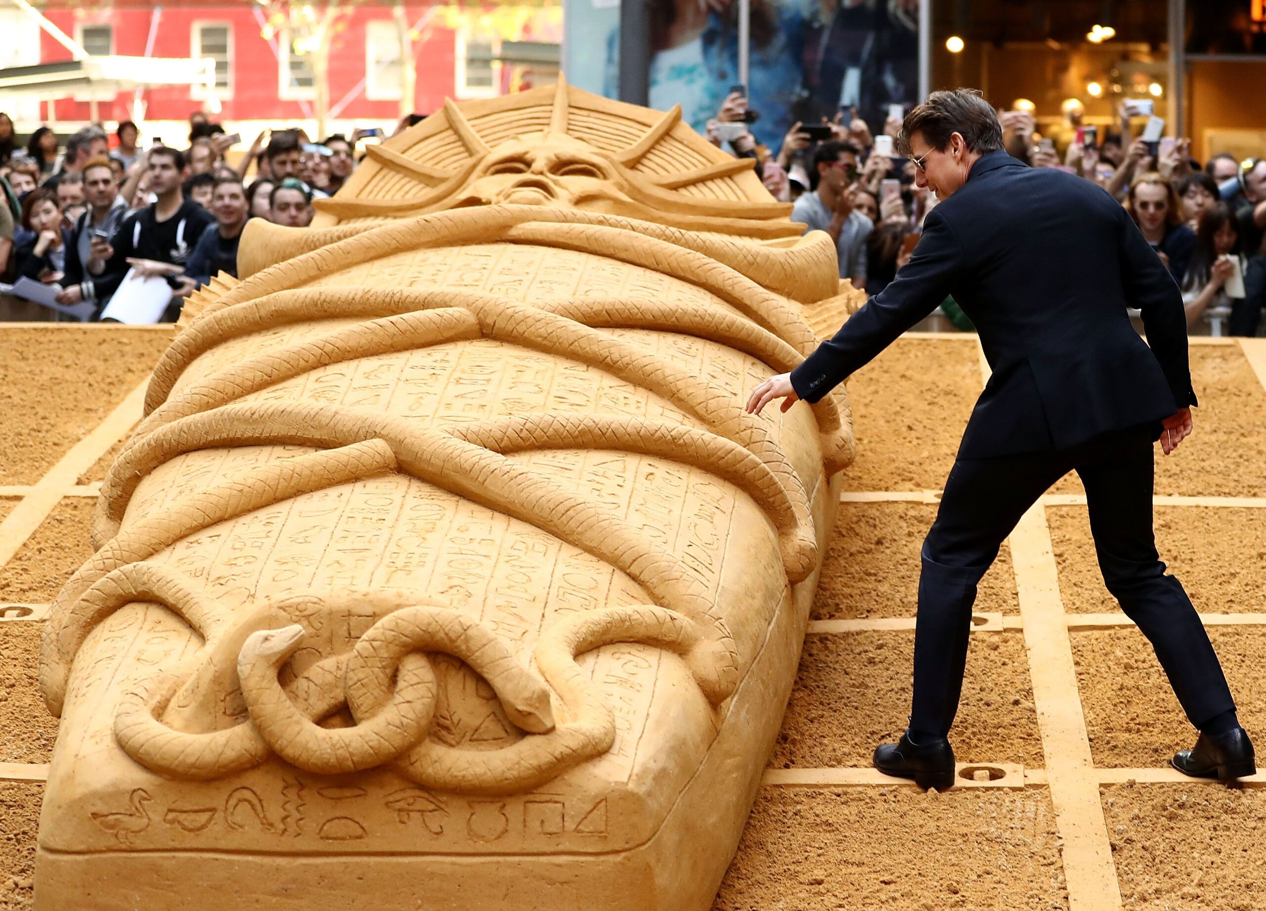 Tom Cruise touches the Mummy sand sculpture during a photo call for The Mummy at World Square on May 23, 2017 in Sydney, Australia.