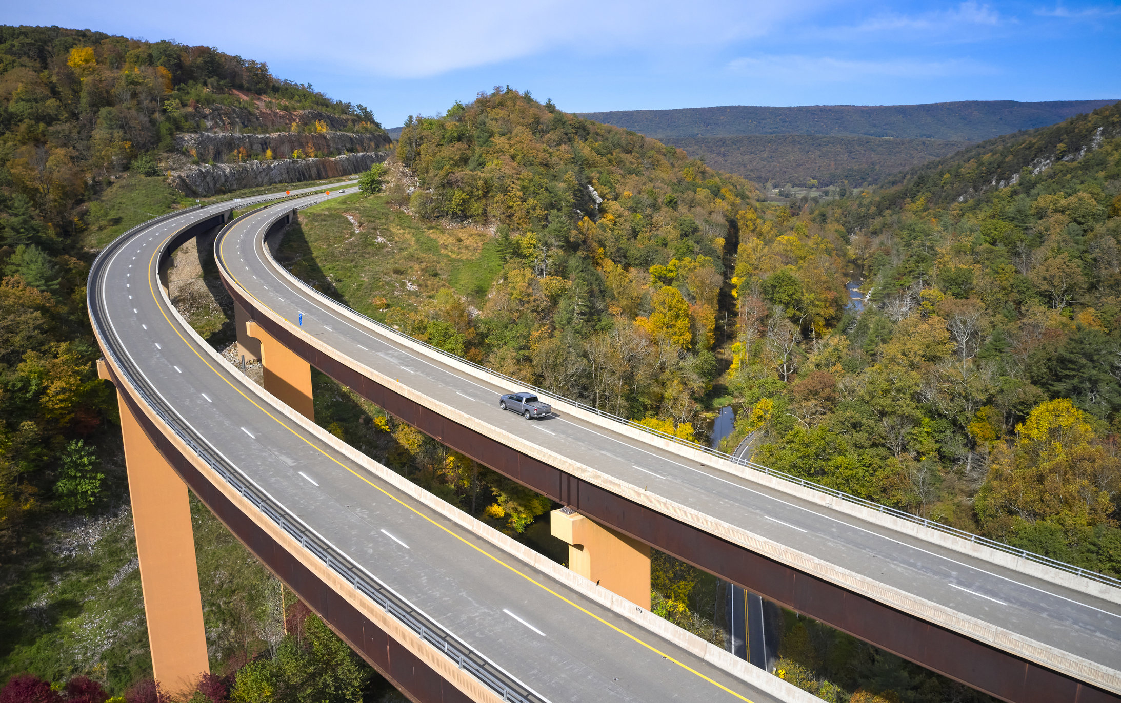 Aerial view of U.S. Route 48 bridge stretching over lost river in the Appalachian Mountains, West Virginia, one lone car on the right road, surrounded by trees