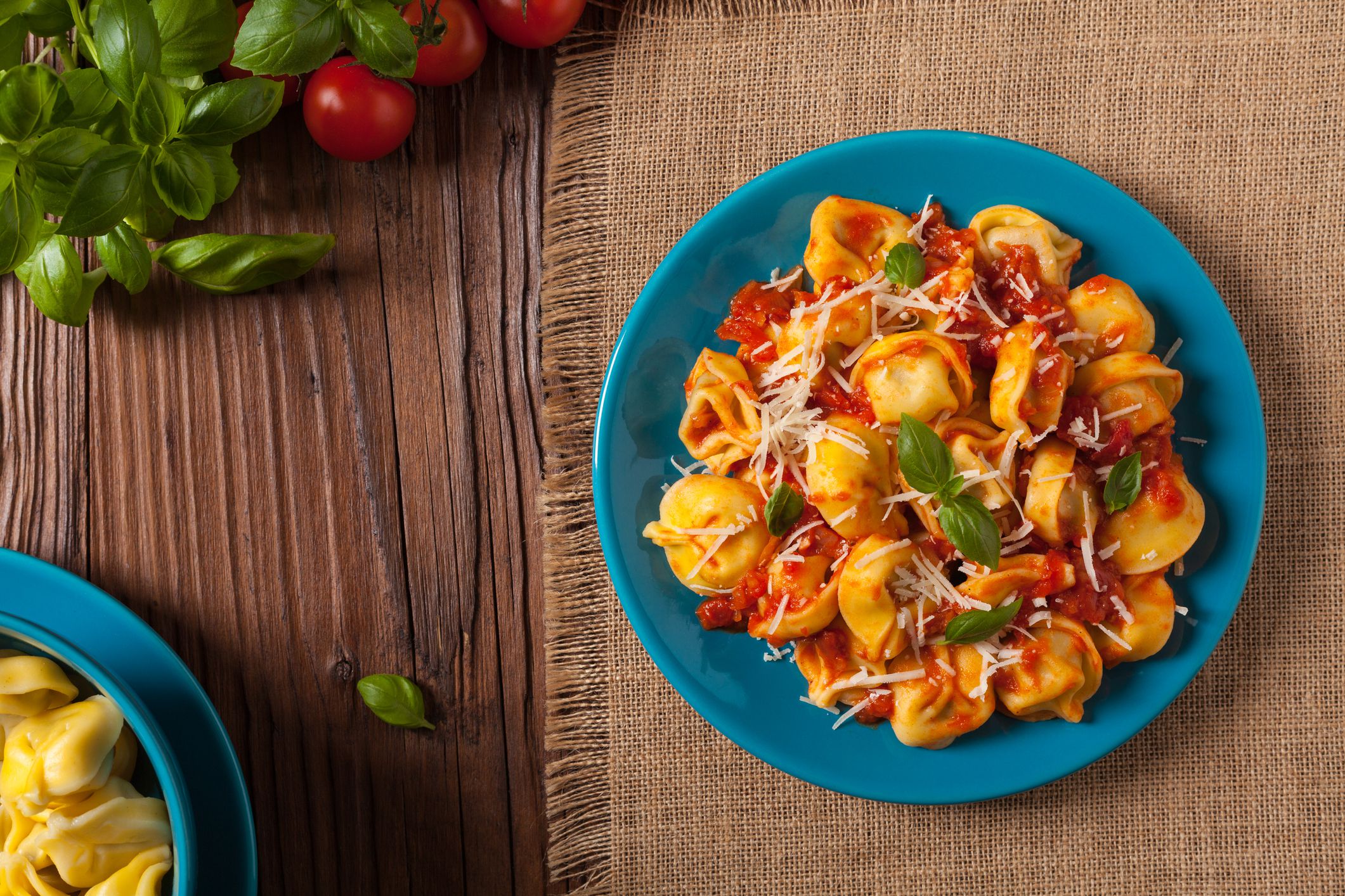 Delicious tortellini with meat in tomato sauce, sprinkled with parmesan cheese and basil. Top view.