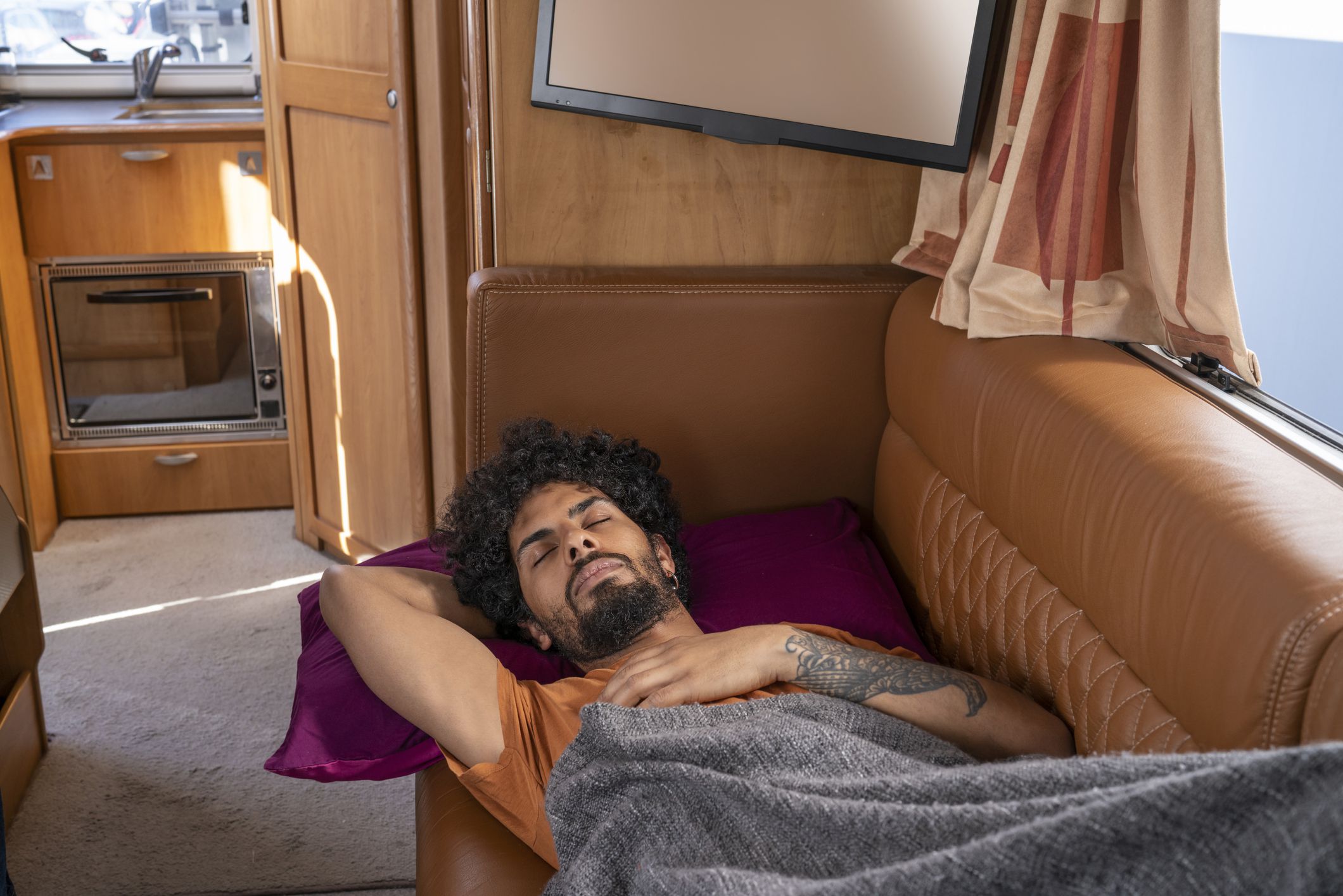 Ethnic young man sleeping in camper van motorhome