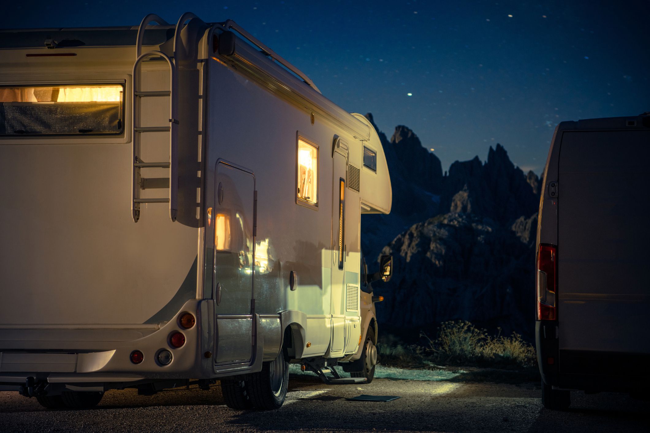 Recreational Vehicle RV Camper Van Camping in the Middle of Alpine Region. Night Time on the Campsite. Scenic View RV Park Pitch.