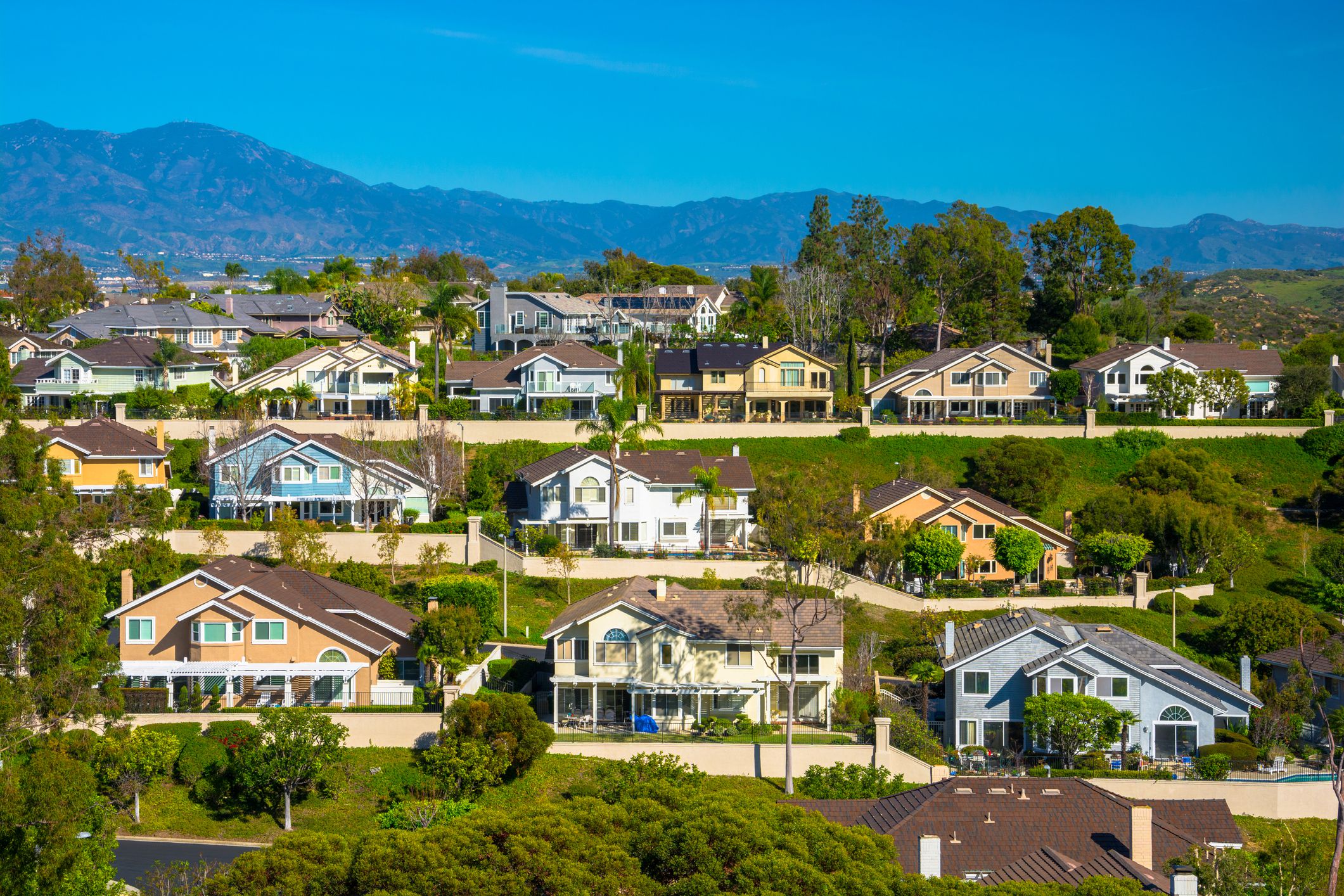 A hillside with many houses in Irvine in southern Orange County, California, with mountains in the background.