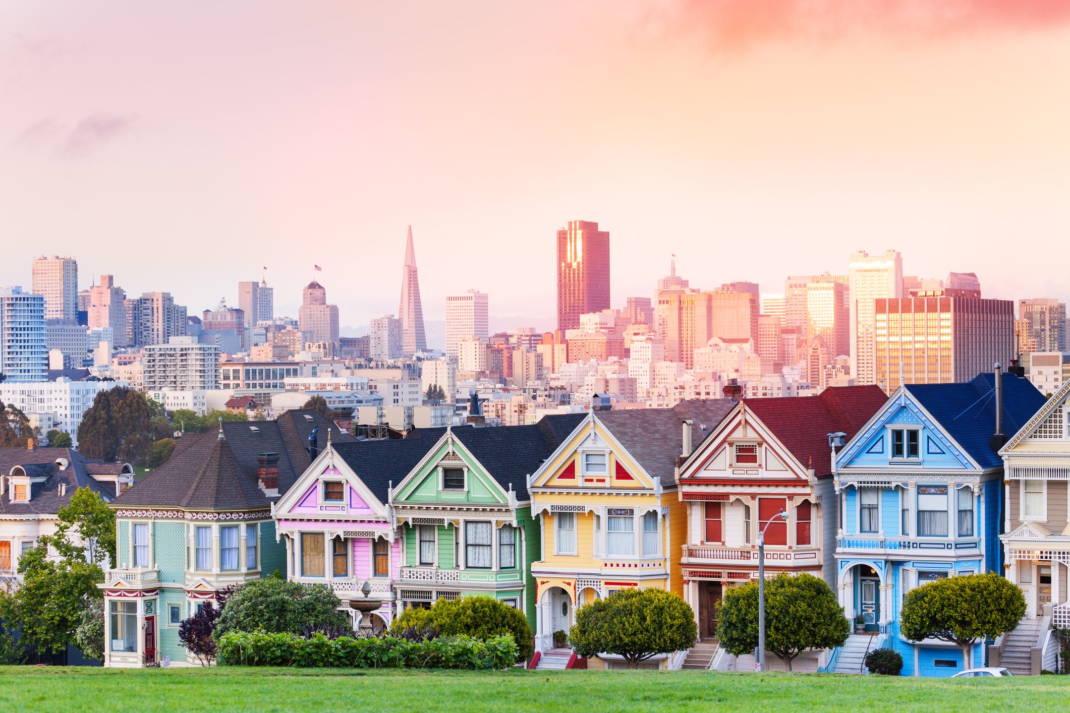 Early evening warm light skyline of San Francisco and painted ladies from Alamo park square
