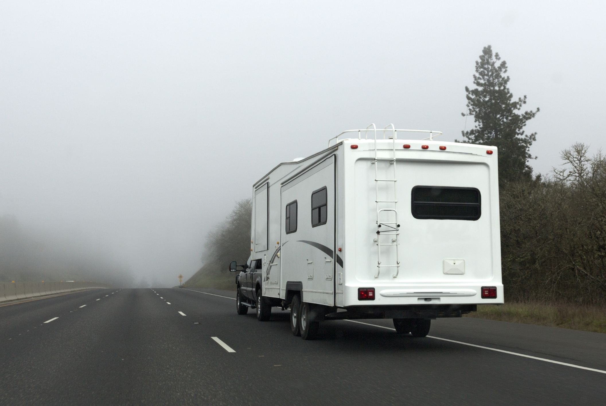 White camper vehicle in high mountain fog. Horizontal.