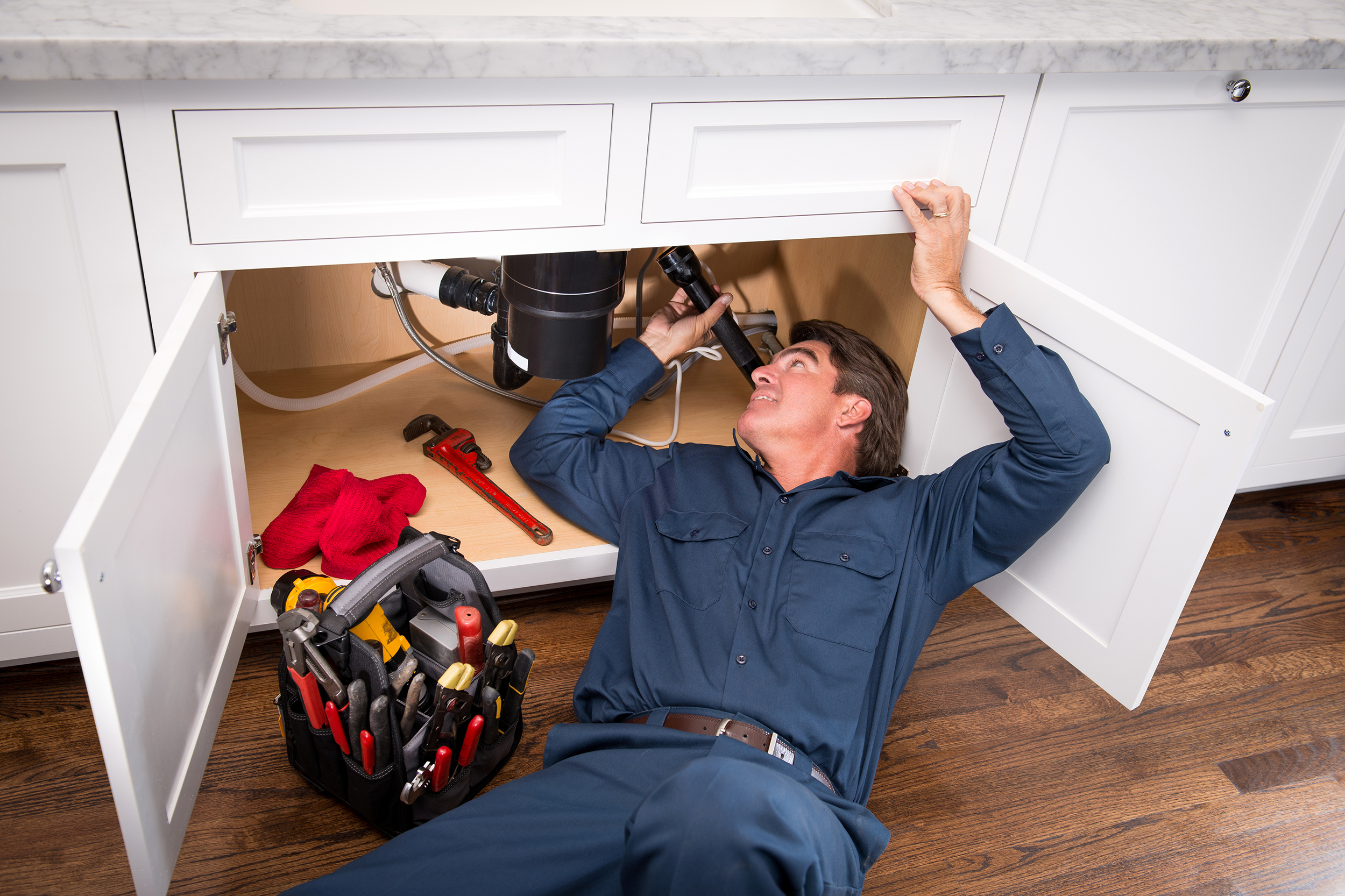 plumber working on pipes under the kitchen sink