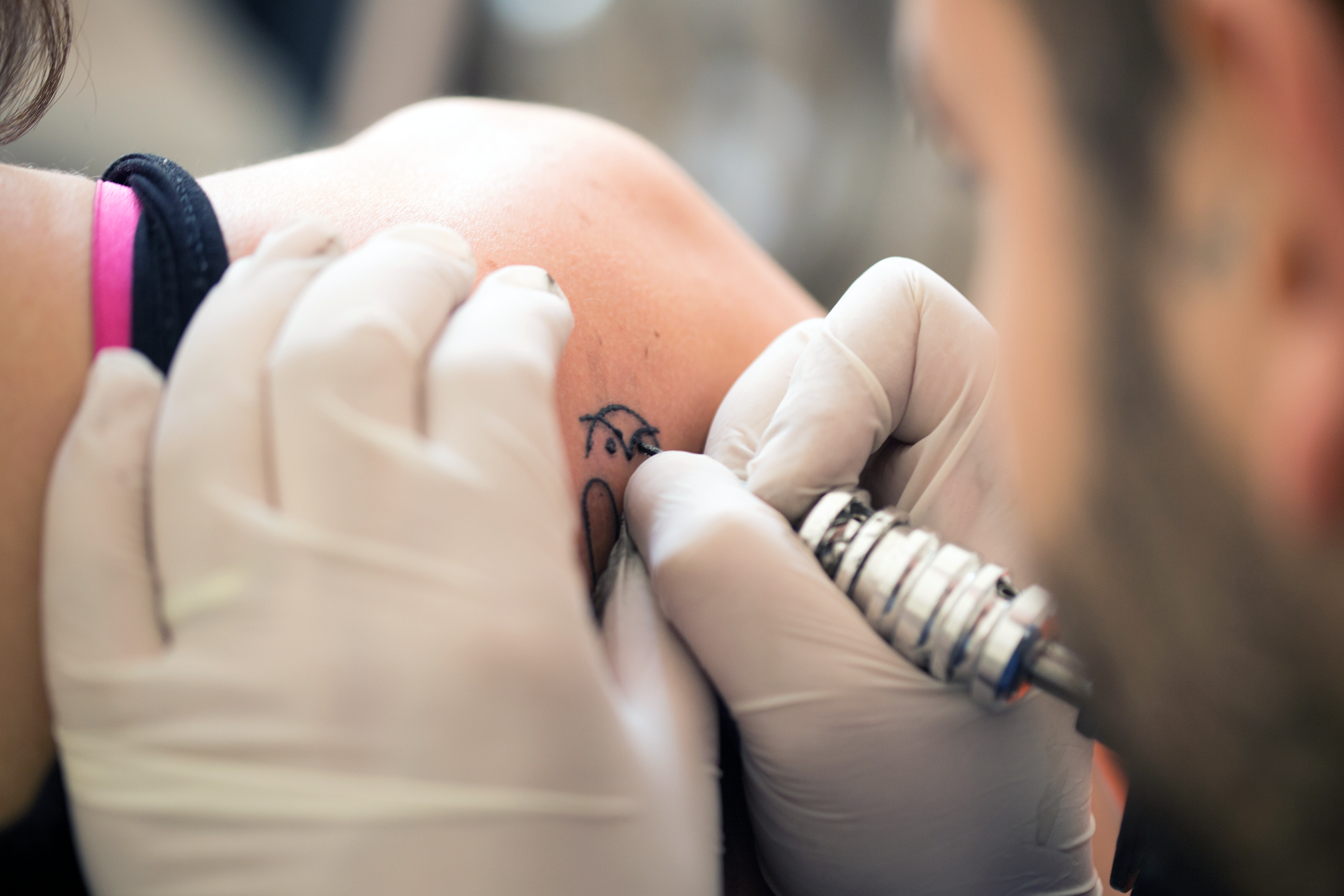 woman receiving a tattoo on her shoulder blade