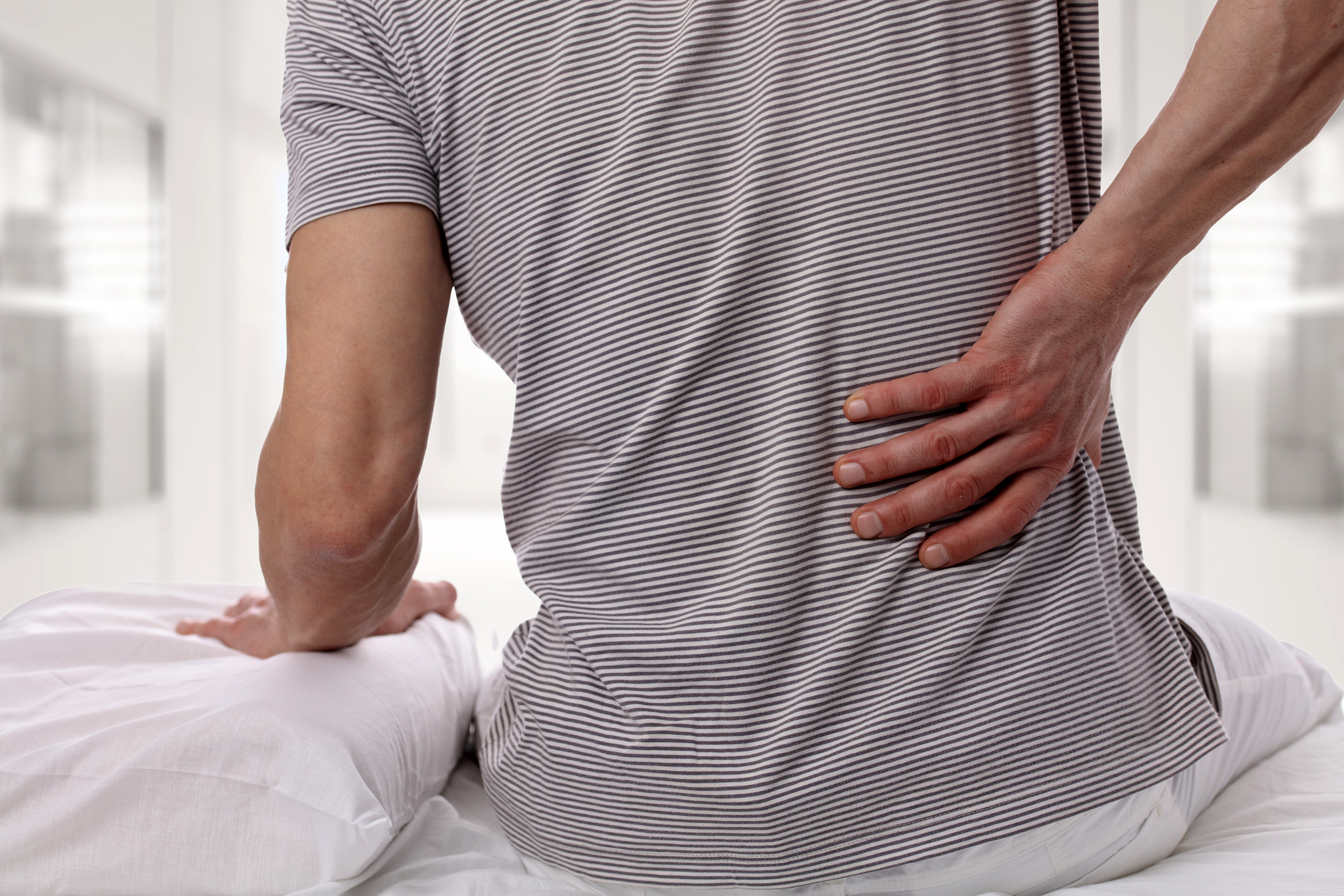 man experiencing back pain from his mattress