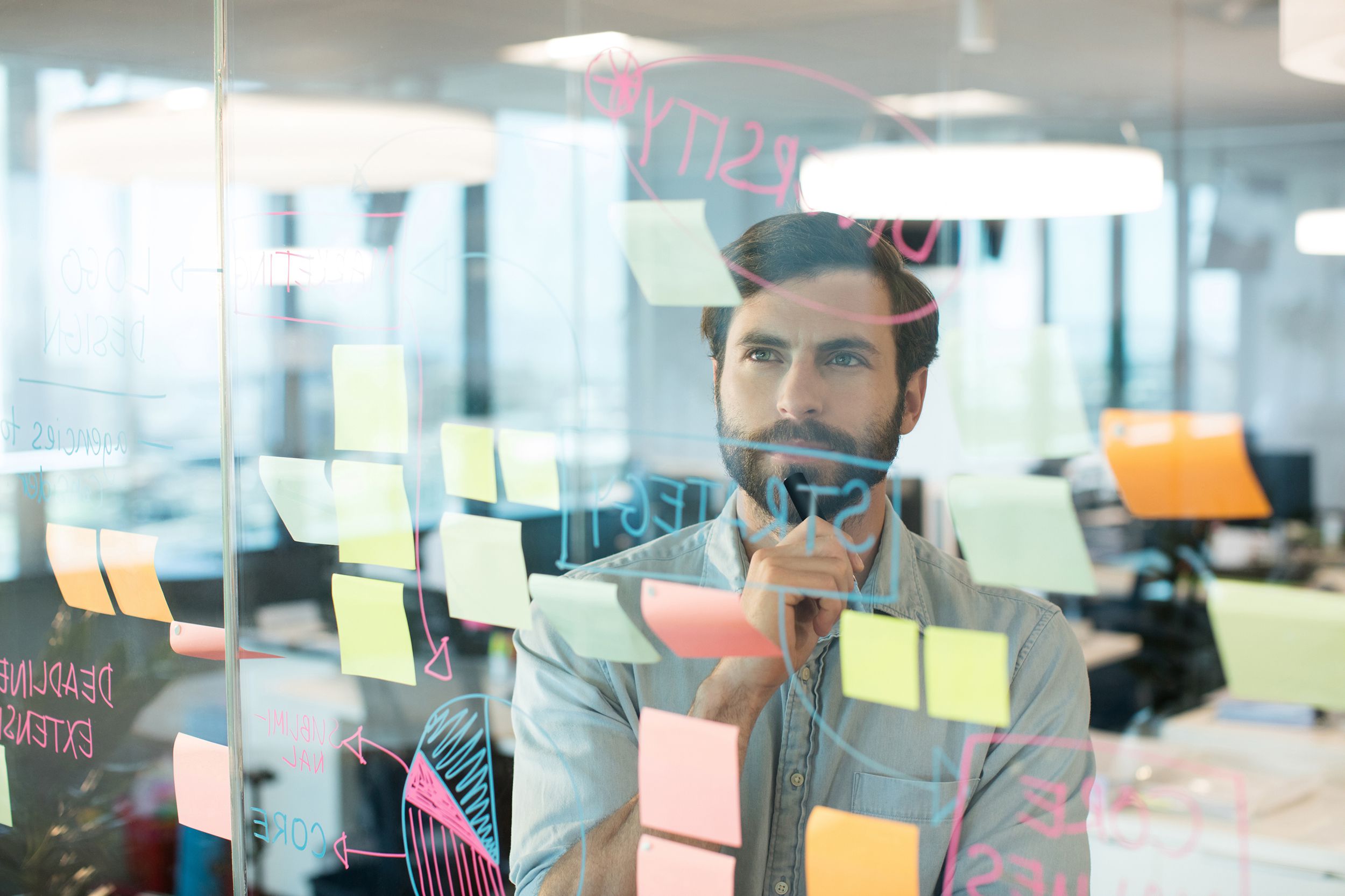thoughtful businessman looking at strategy written on glass